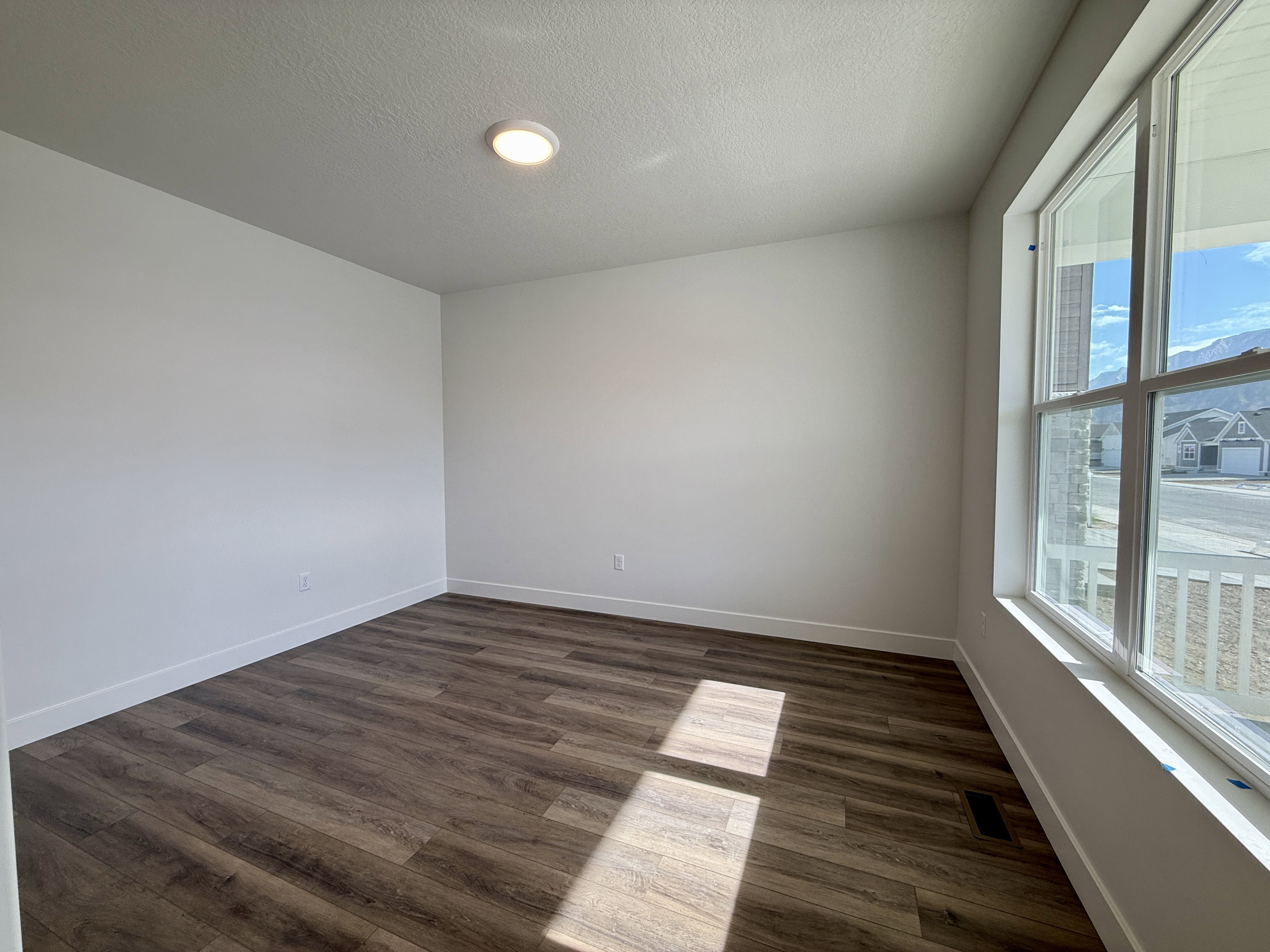 Spacious room featuring wood-finish flooring, recessed ceiling lighting, and a large window with white trim