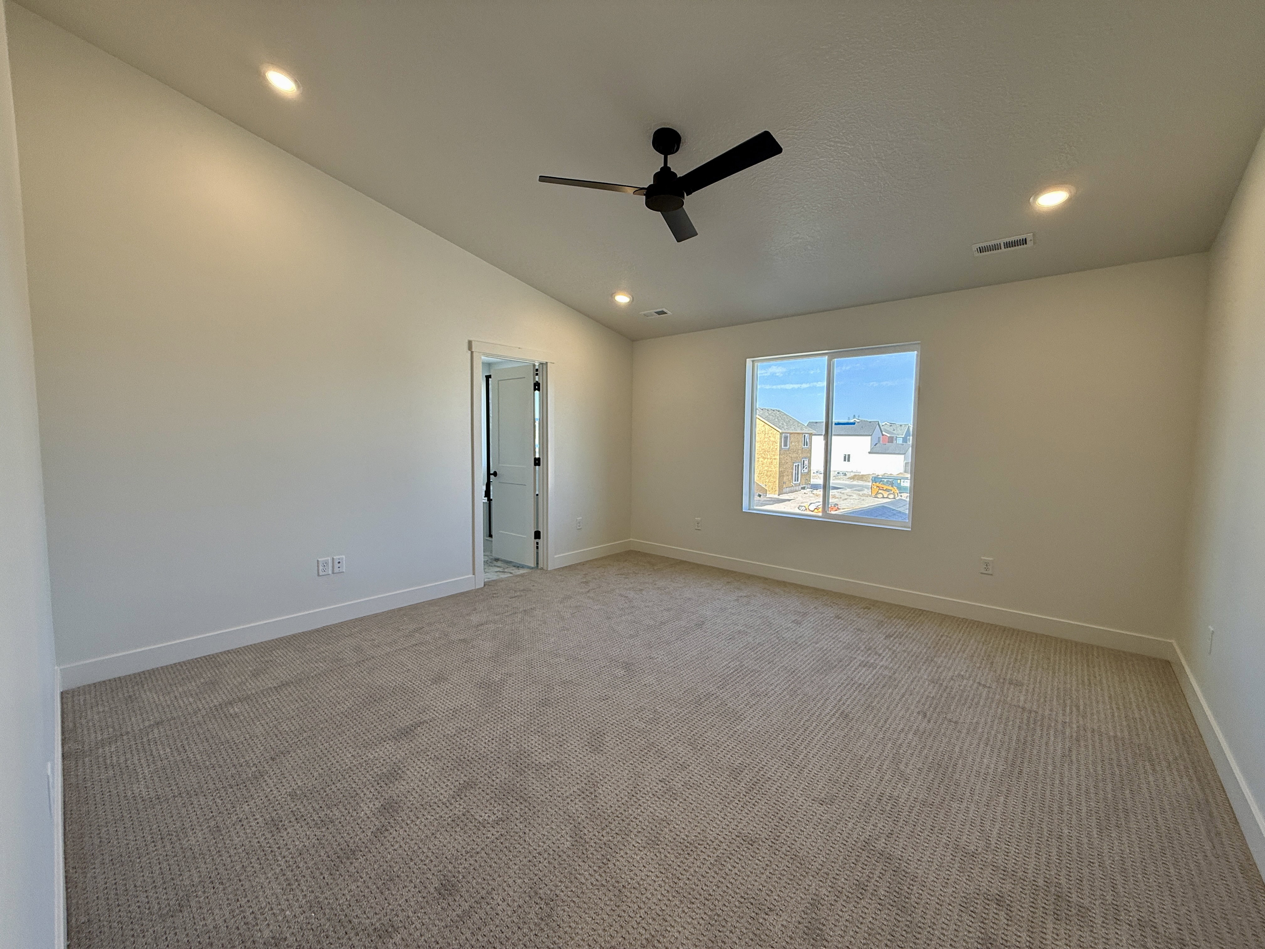 Spacious room featuring vaulted ceilings, recessed lighting, a modern ceiling fan, large windows, and neutral carpeting