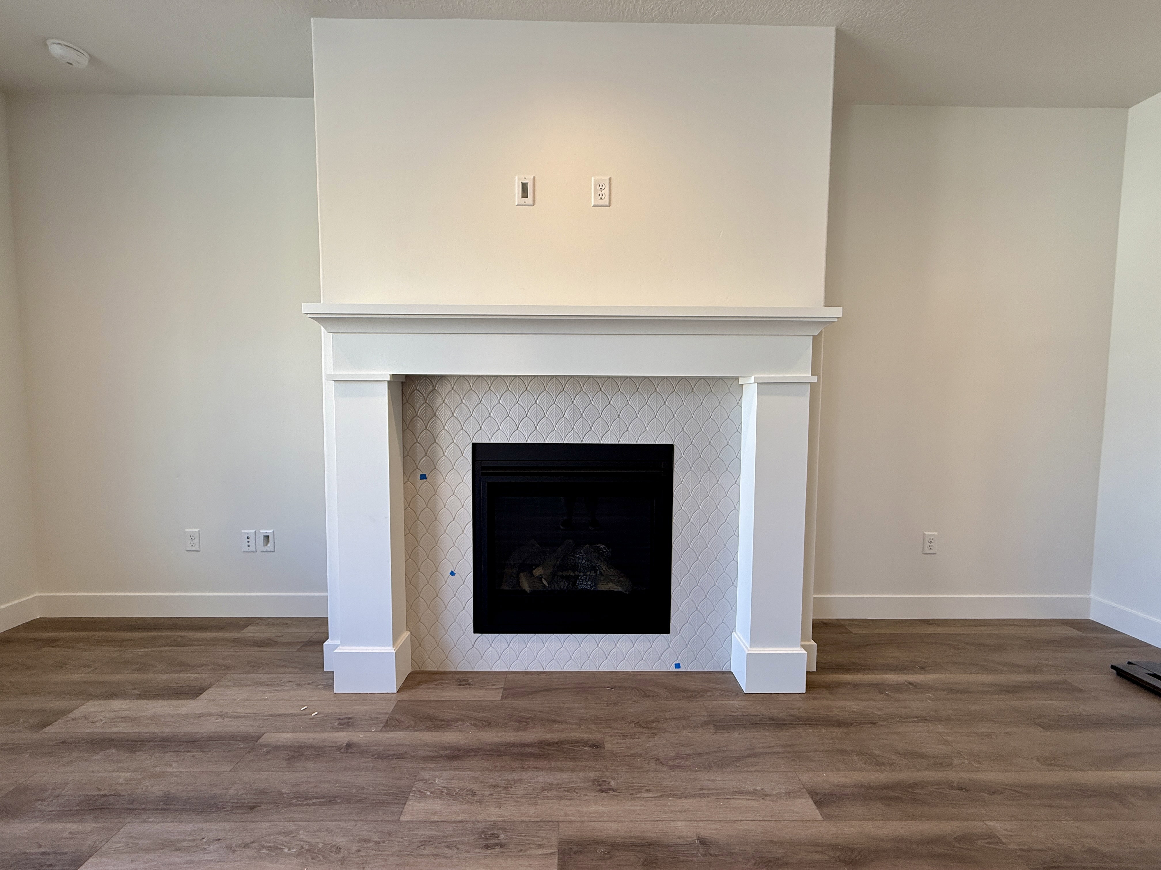 Fireplace featuring a white mantel, geometric tile surround, and a black firebox