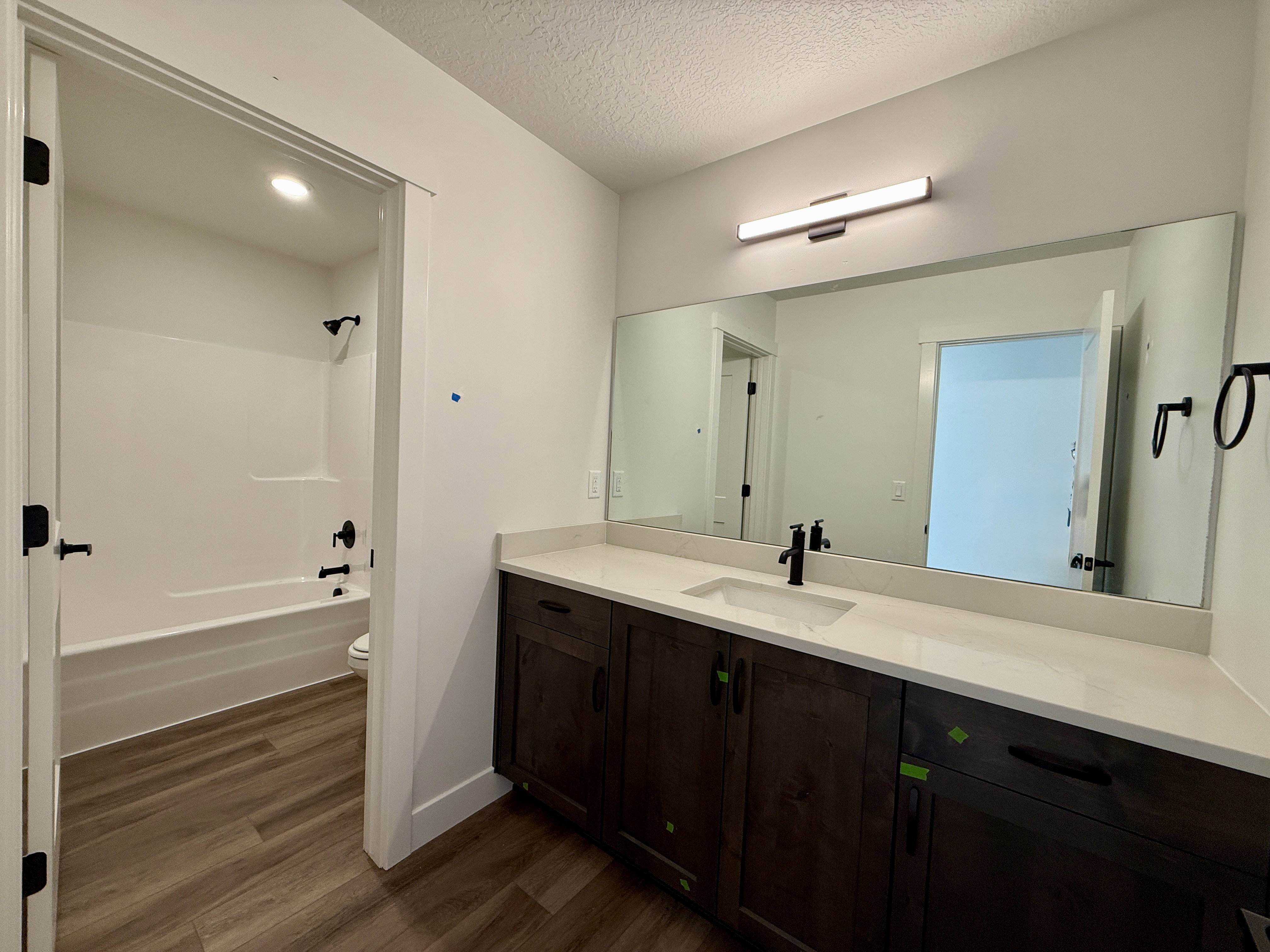 Bathroom featuring a dark wood-finish double vanity with a light-toned countertop, an integrated rectangular sink, and a large wall-mounted mirror