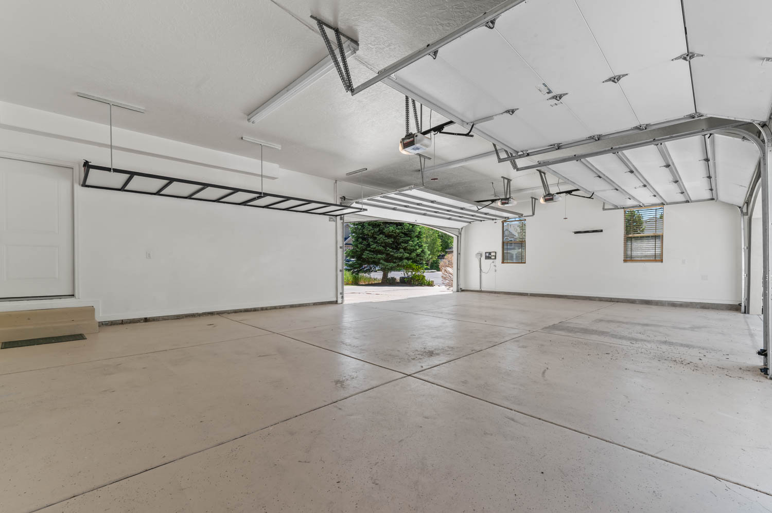 Spacious garage featuring a light-toned concrete floor, white walls, and a white access door