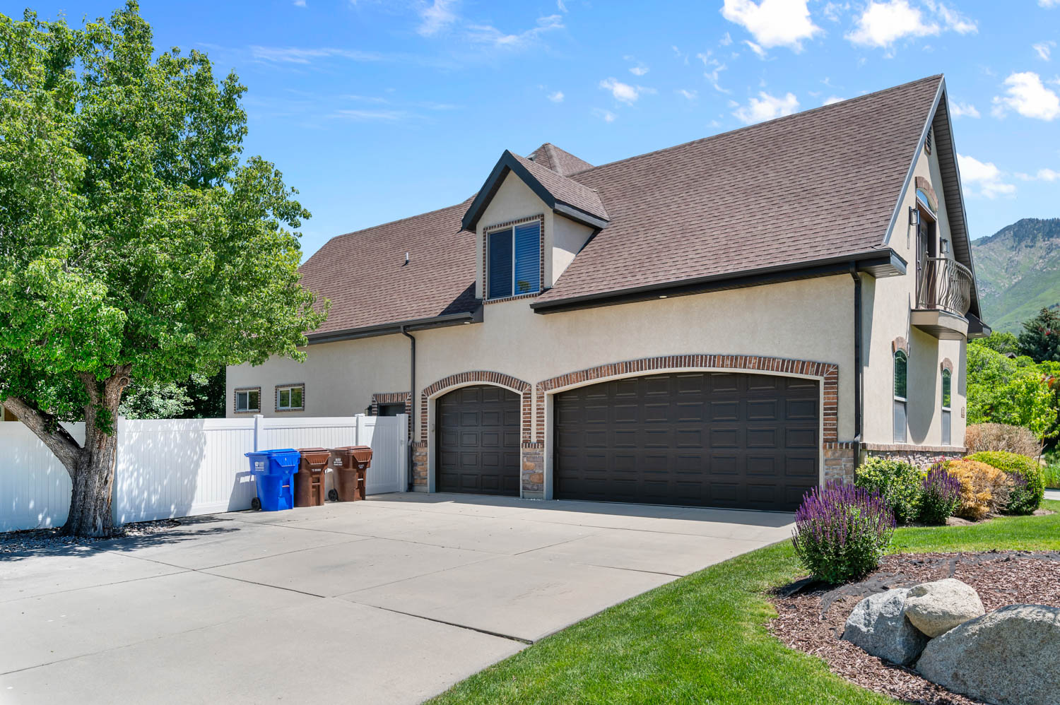 Stucco exterior featuring a two-car garage with arched brick detailing