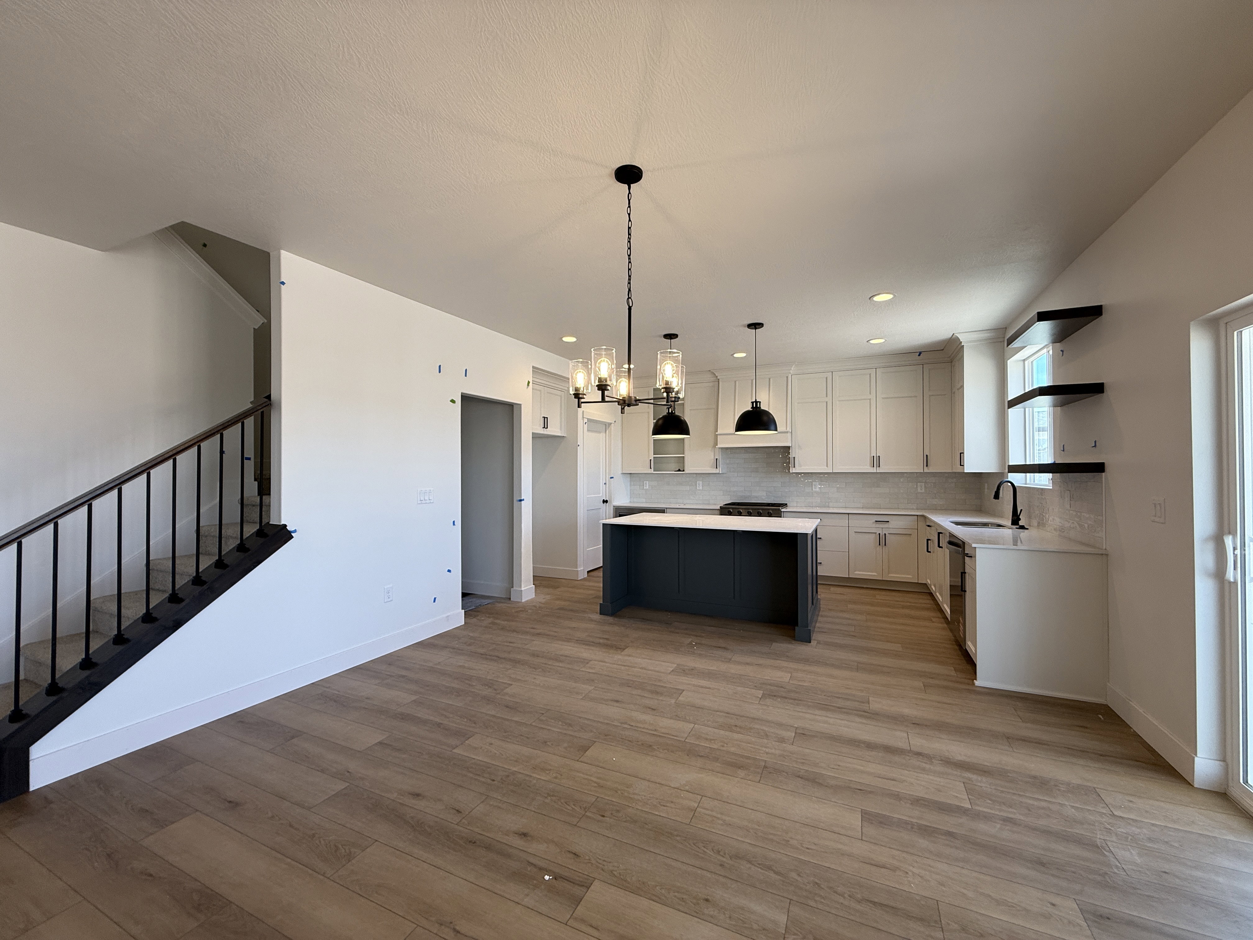 Open-concept kitchen featuring an island with stone countertop, white shaker cabinetry, and wood-finish flooring