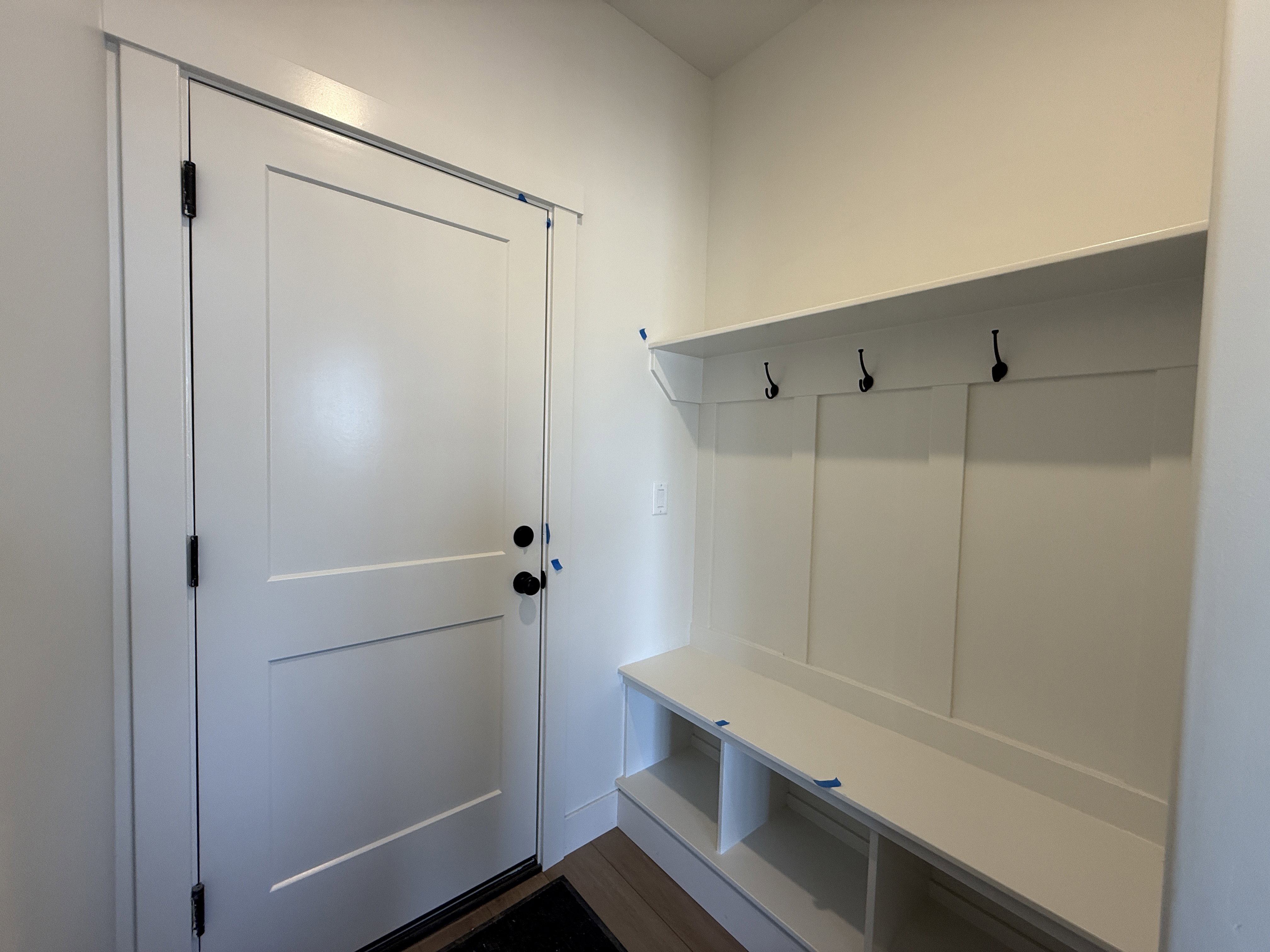 Built-in mudroom bench with cubby storage, upper shelf, and three coat hooks