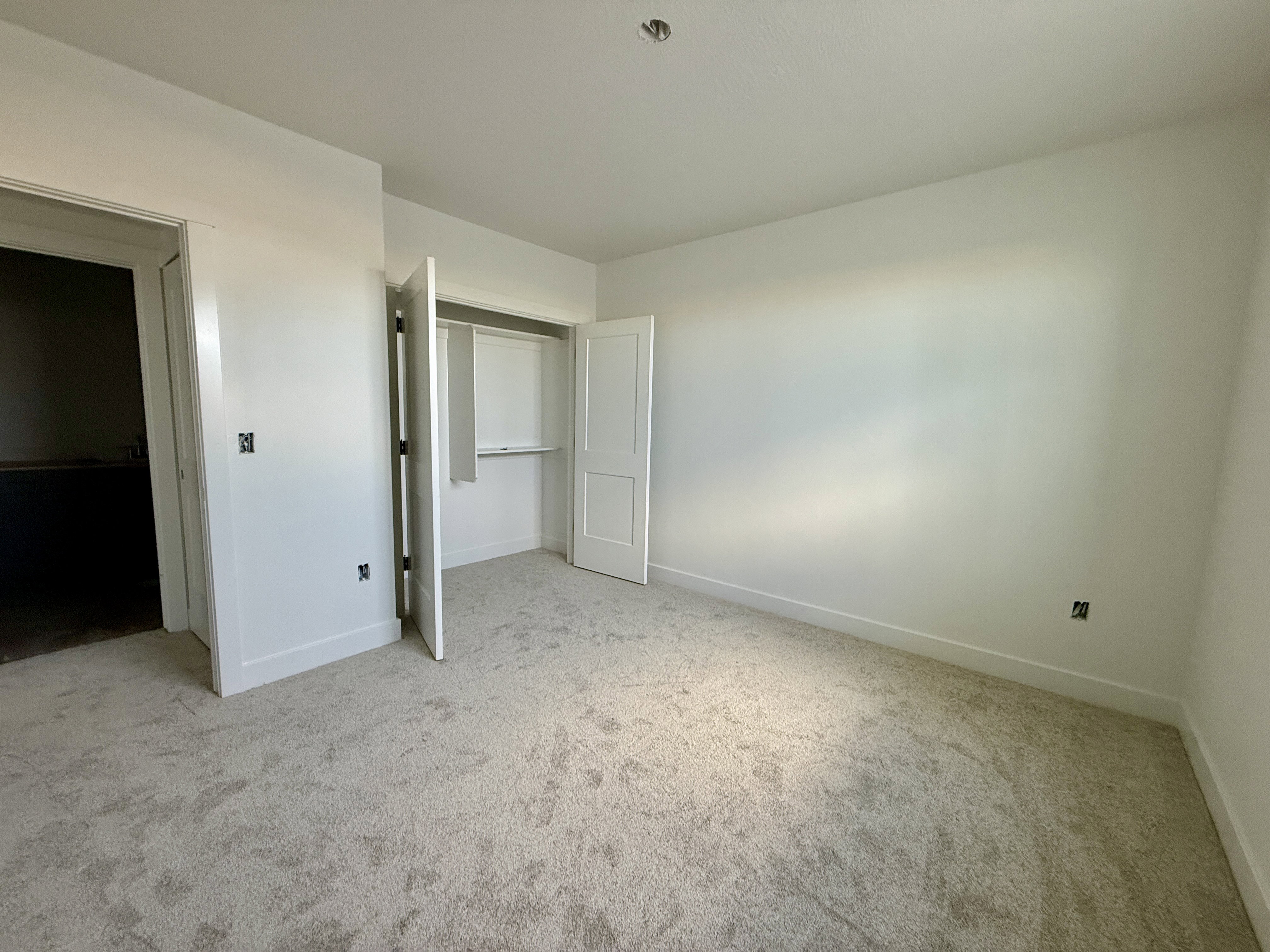 Neutral tone carpeting with white baseboards and walls