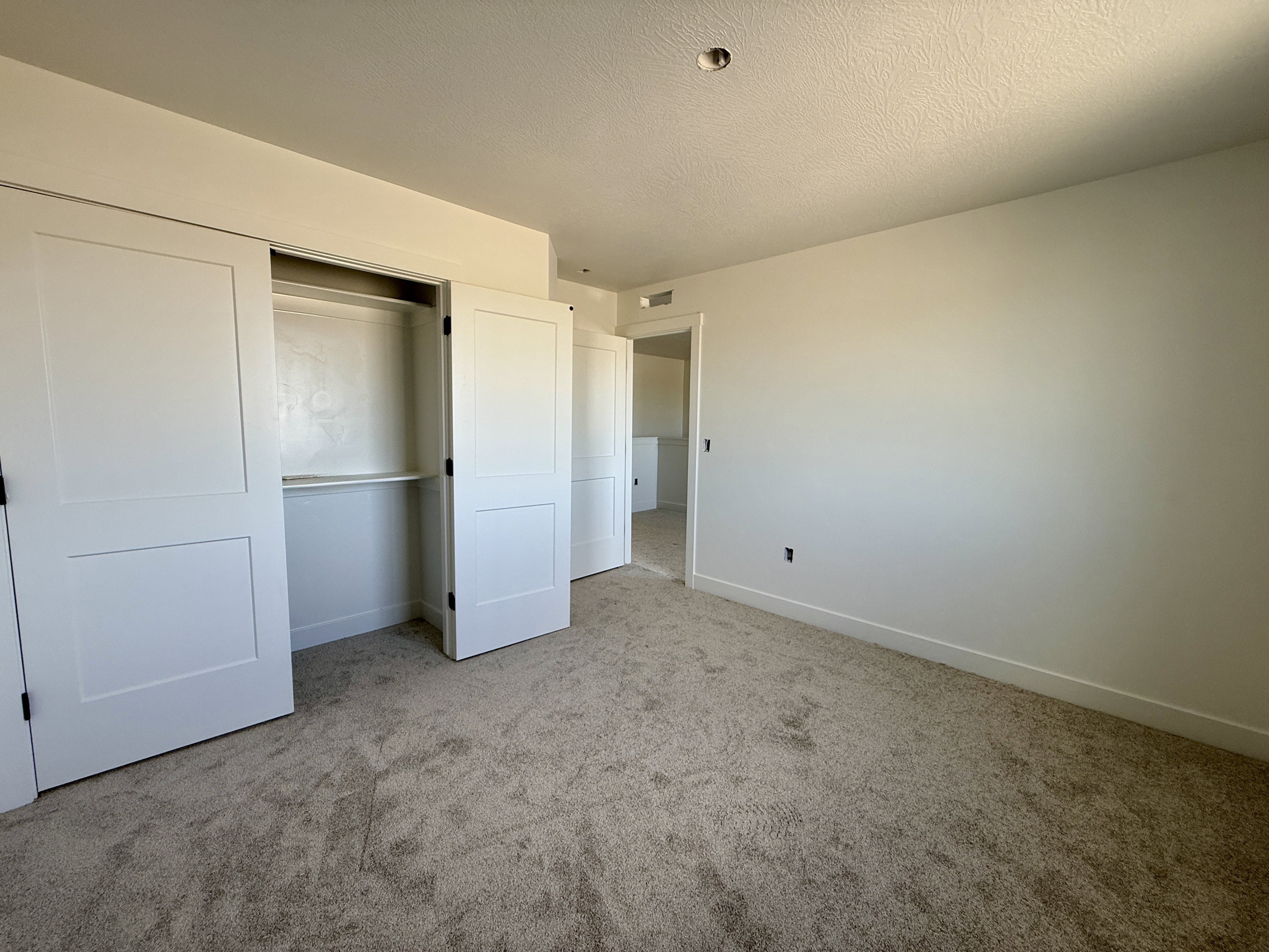 Carpeted room featuring a double-panel sliding closet, built-in shelving and hanging rod, white baseboards, and a neutral wall color