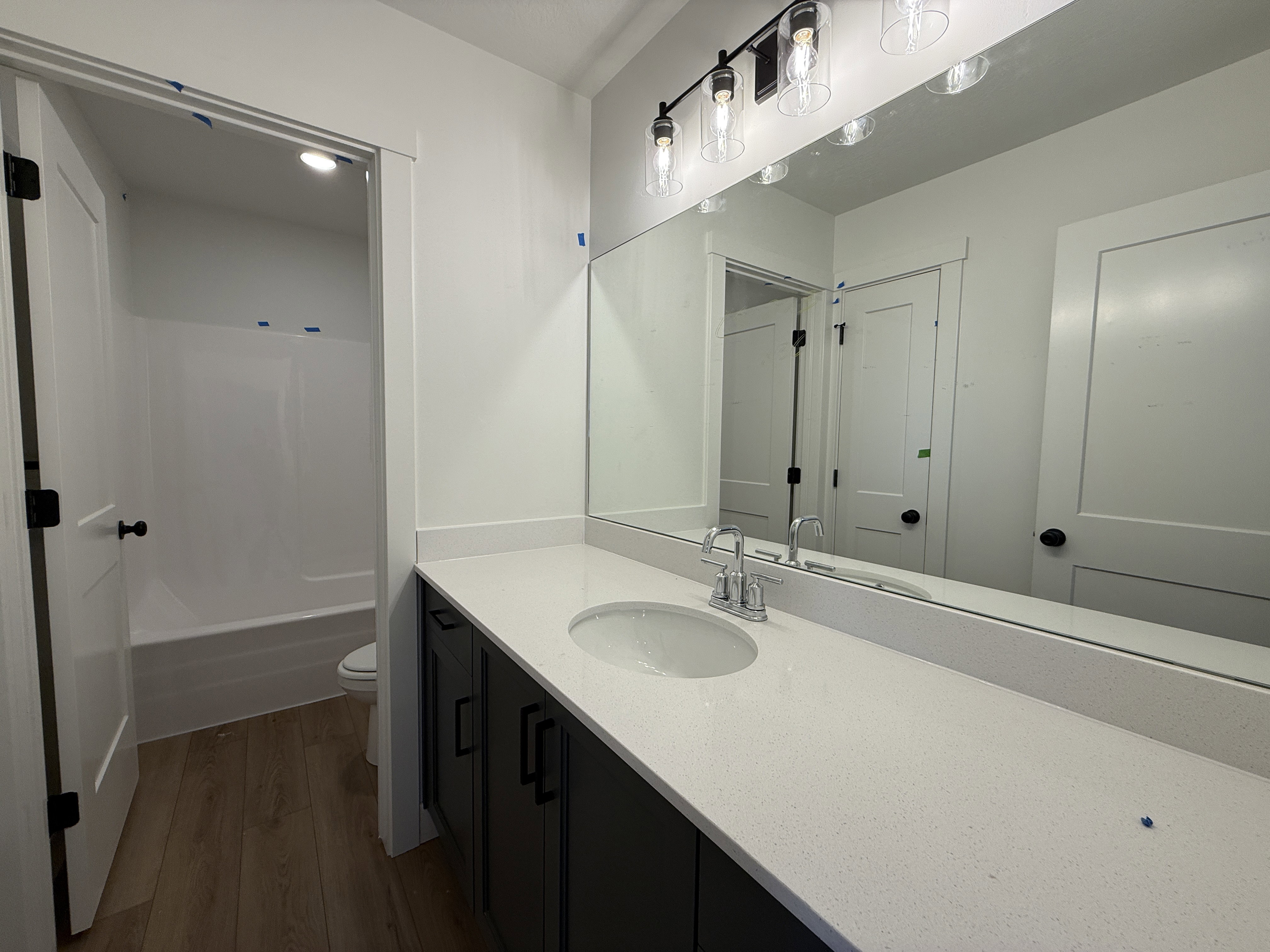 Bathroom vanity with a white solid surface countertop, an undermount sink, and a chrome faucet