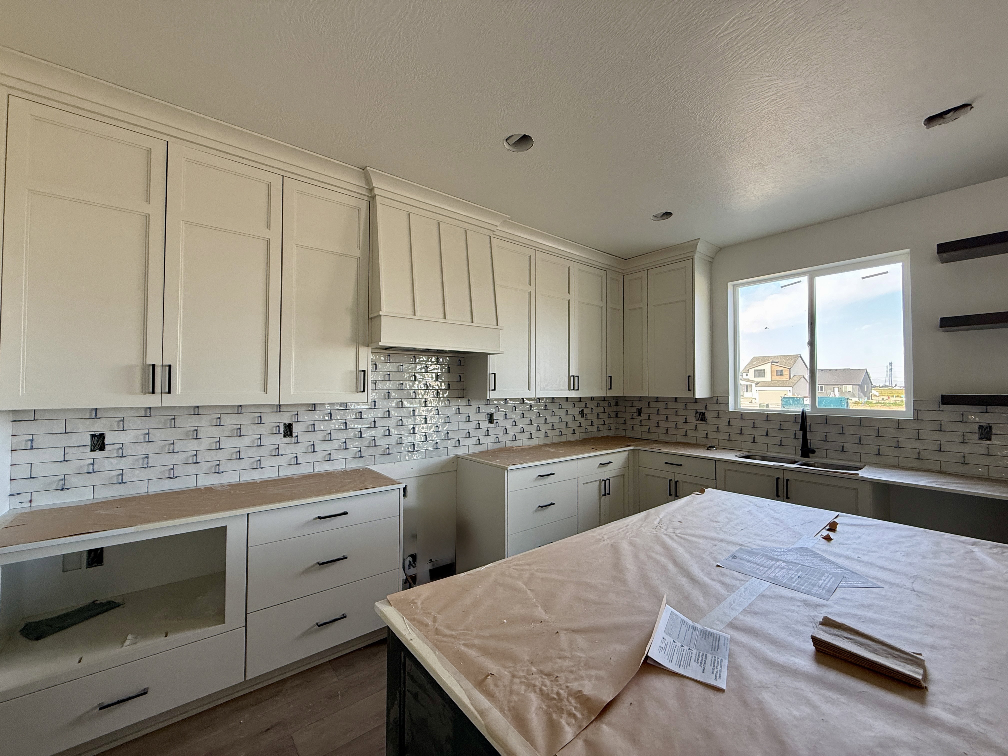 Kitchen featuring light-toned cabinetry, a subway tile backsplash, and a large central island