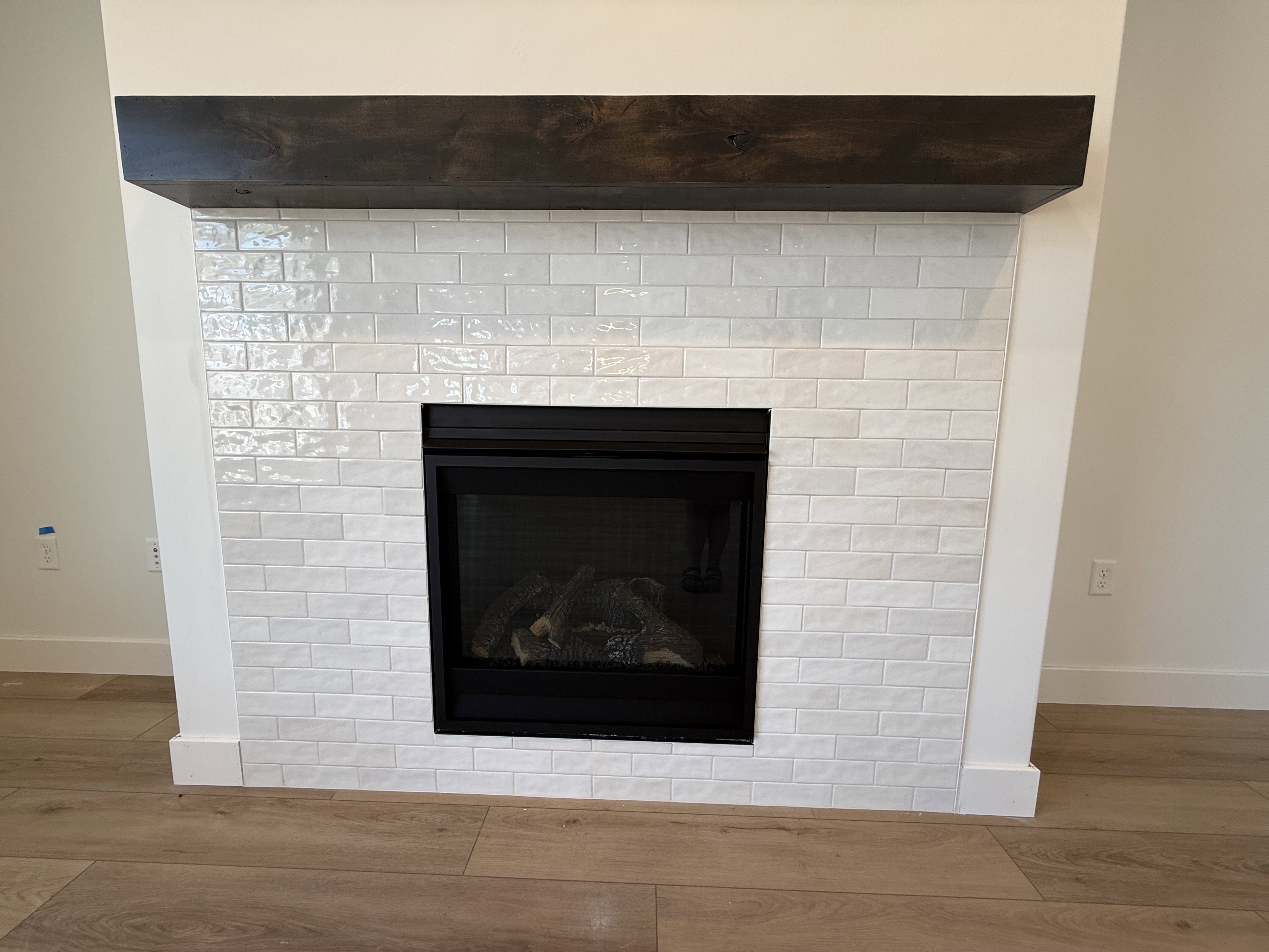 Fireplace featuring a dark wood mantel, white subway tile surround, and a black firebox with gas logs