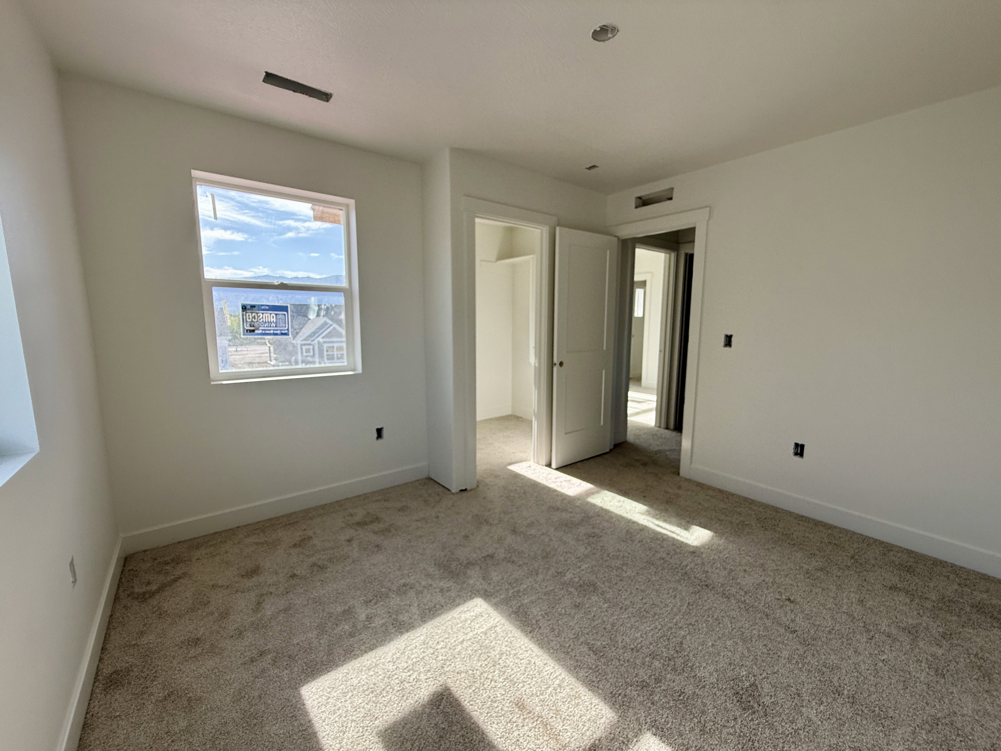 Carpeted interior room featuring white walls and a white window frame