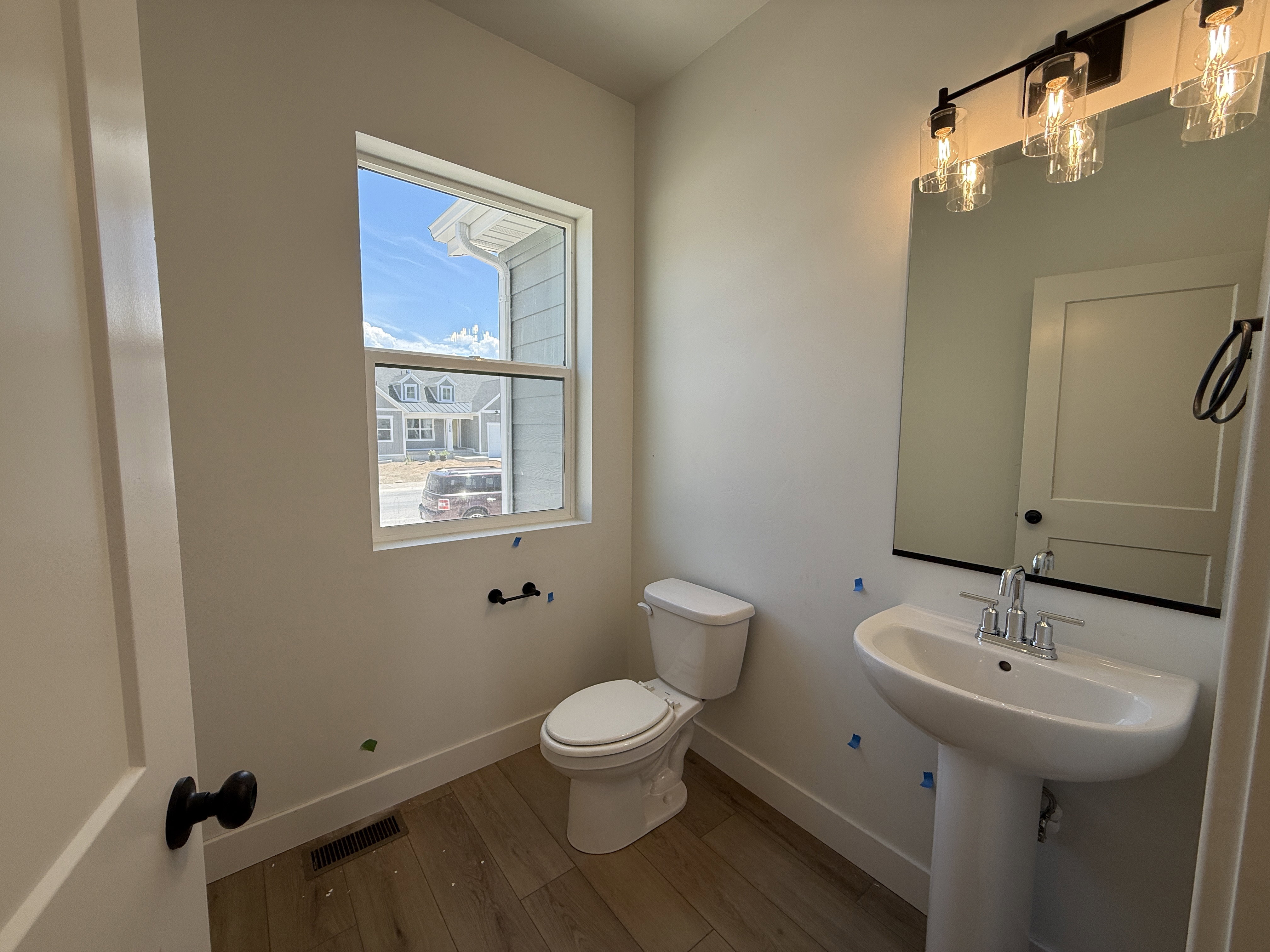 Pedestal sink with chrome faucet, framed mirror, and a contemporary three-light vanity fixture