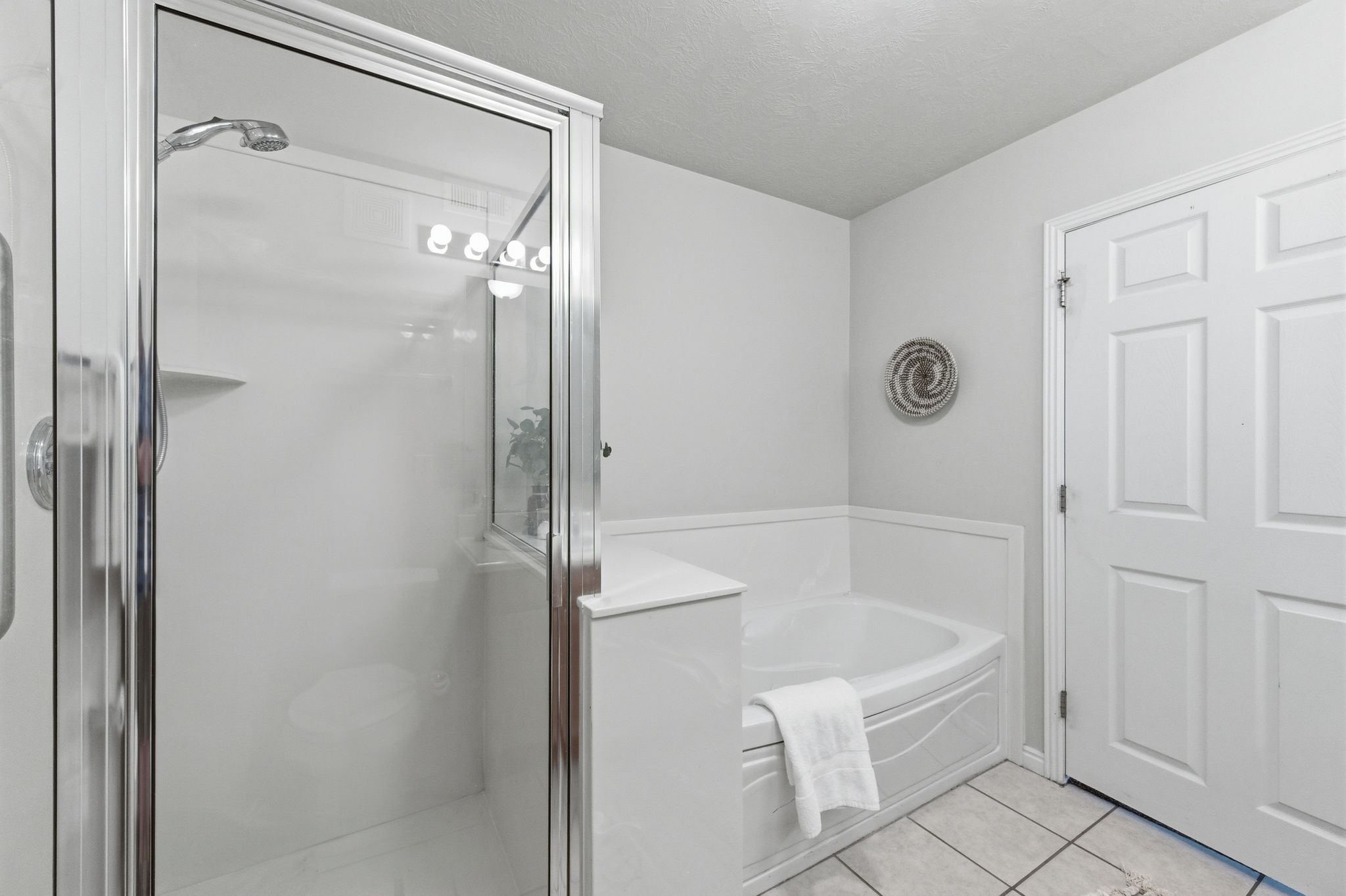 Primary bathroom featuring a glass-enclosed shower with chrome fixtures, a built-in corner bathtub, and white panel doors