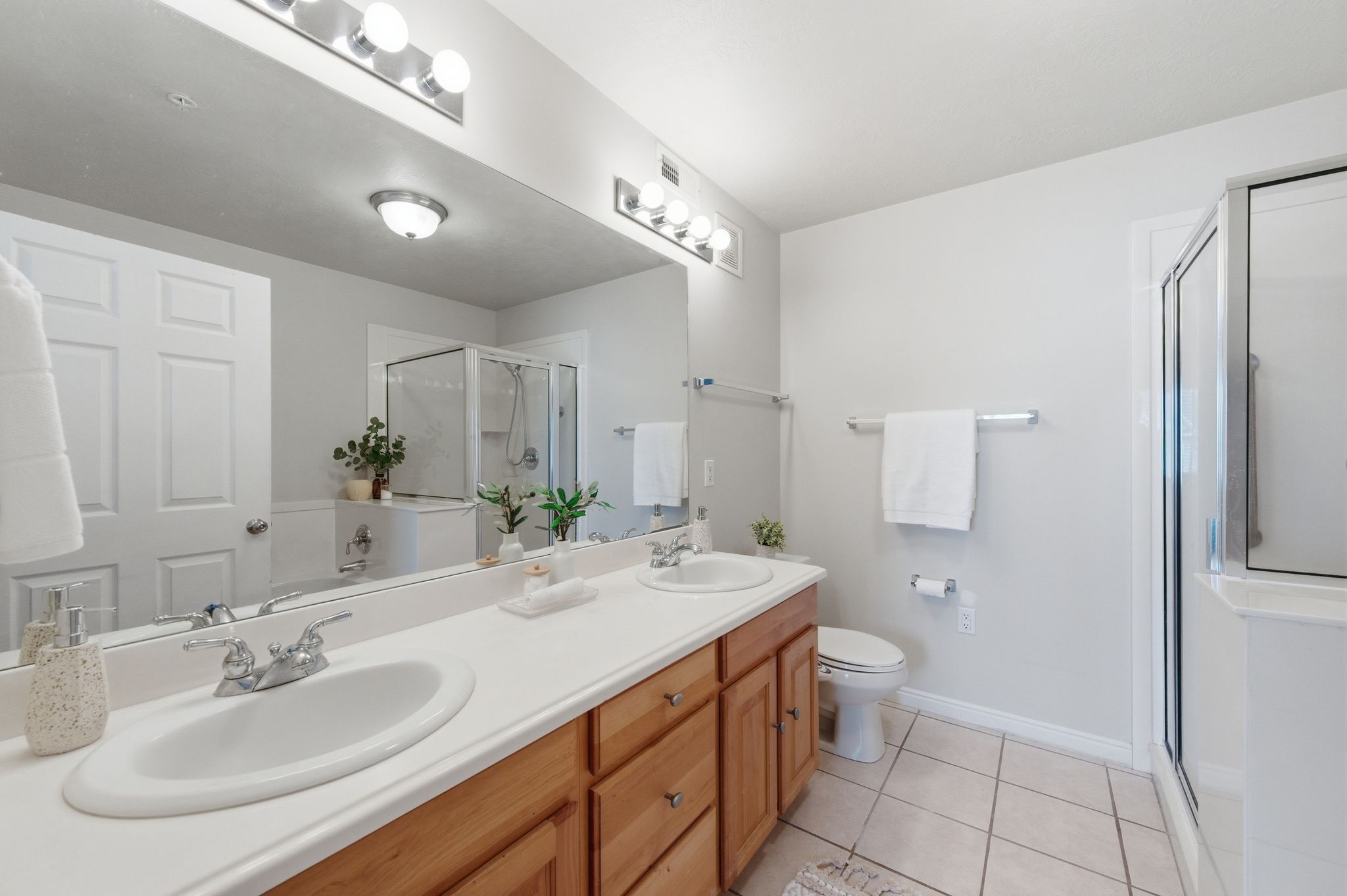 Primary bathroom featuring a double vanity with wood cabinetry, white countertops, and dual undermount sinks
