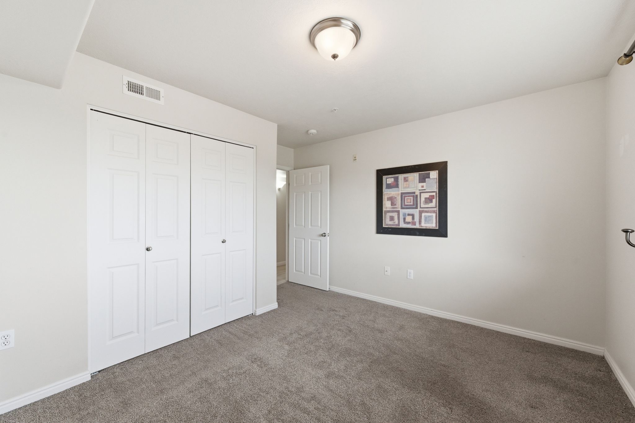 Guest bedroom featuring a plush gray carpet, a white bi-fold closet, and a white interior door