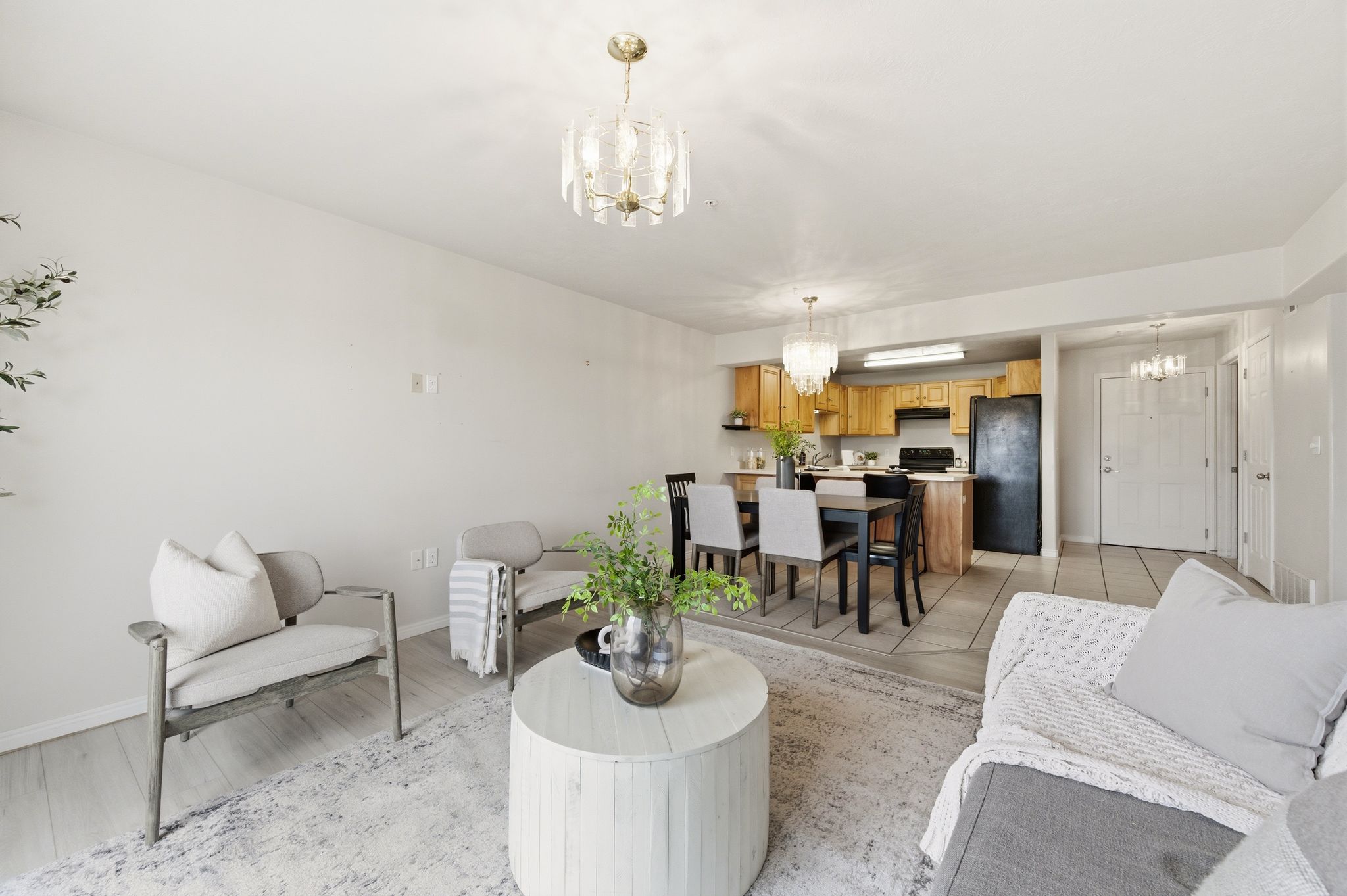 Open-concept living space featuring wood-finish flooring, a contemporary chandelier, and a neutral color palette