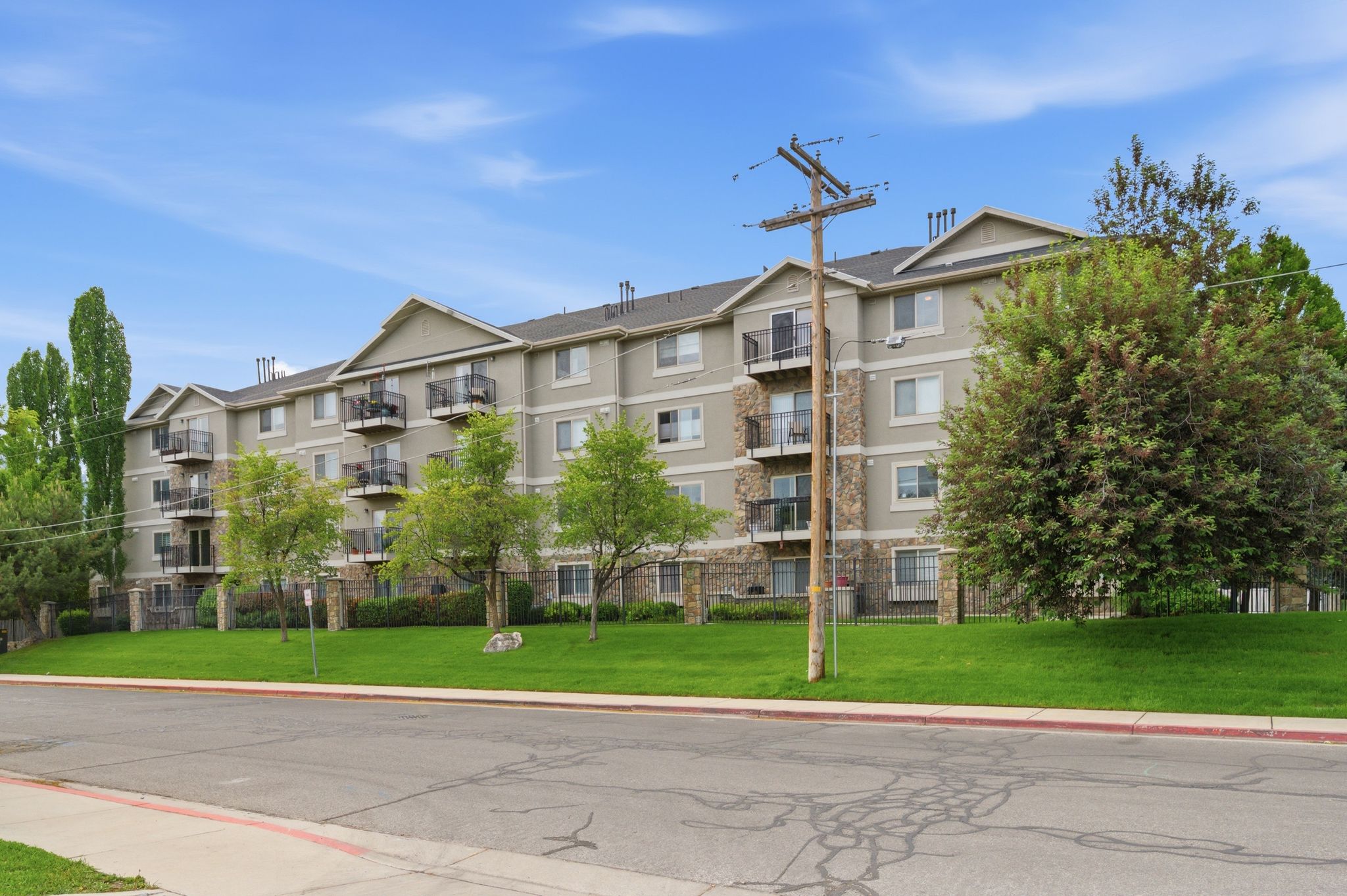 Multi-story building with a stone and siding exterior, featuring multiple private balconies with dark railings