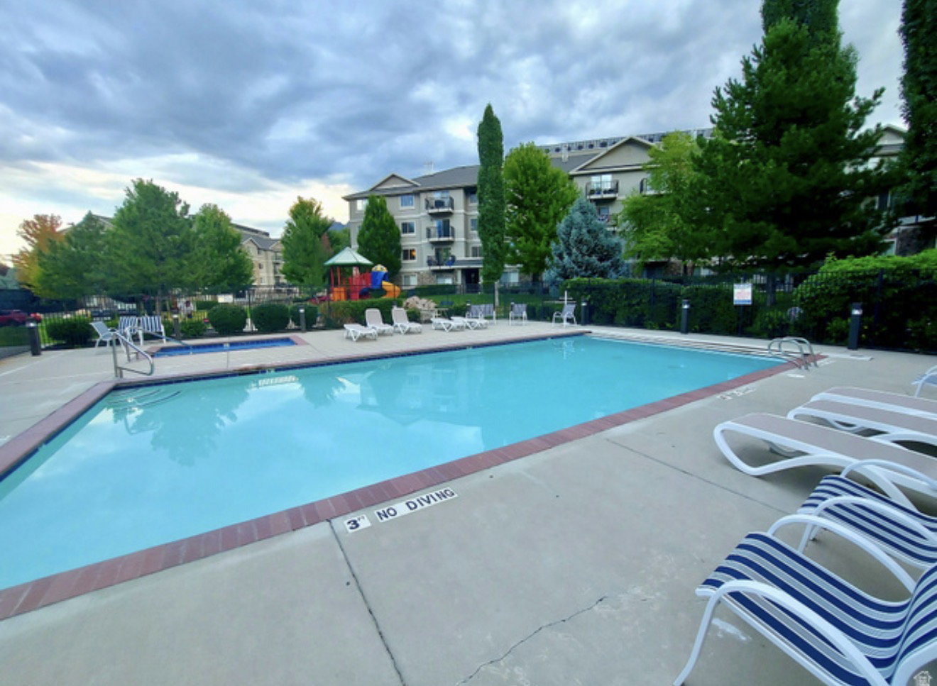 Community swimming pool with an integrated hot tub and surrounding concrete deck