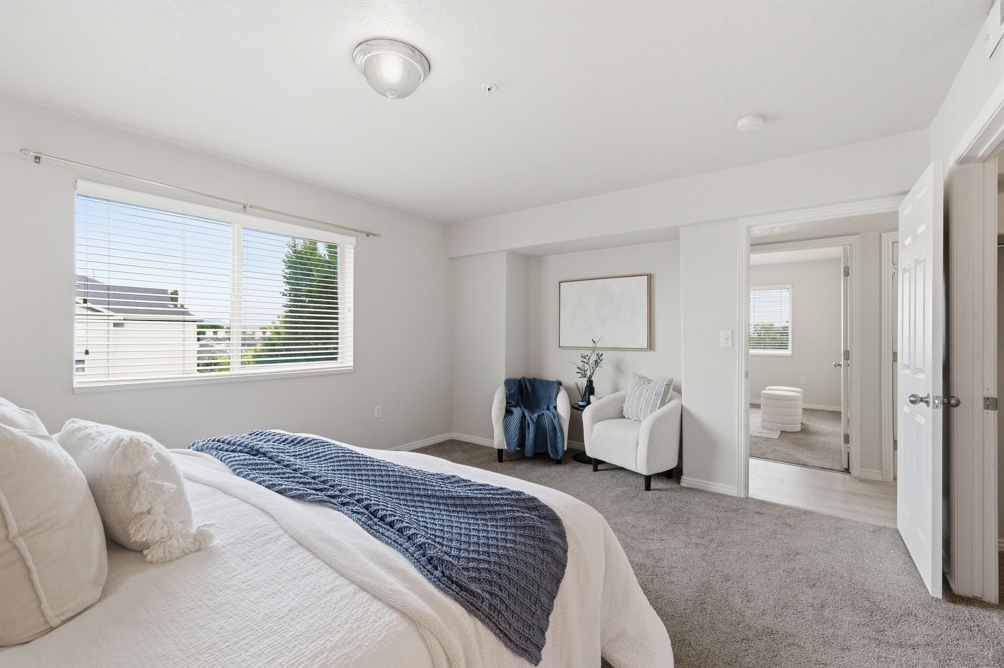 Primary bedroom featuring light gray wall paint, a double window with horizontal blinds, and a built-in recessed area