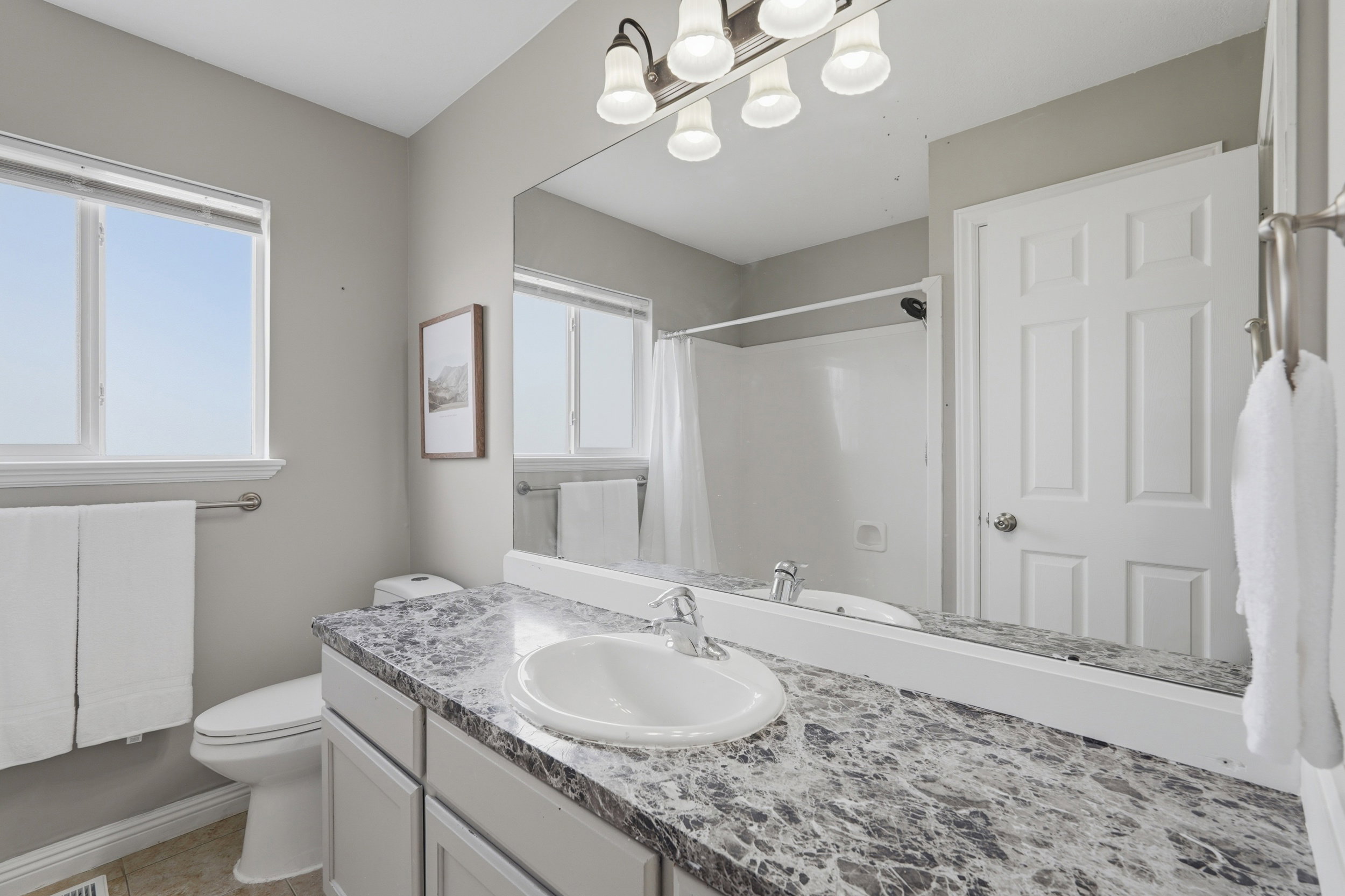 Bathroom featuring a single vanity with a patterned countertop, a built-in sink, and a chrome faucet
