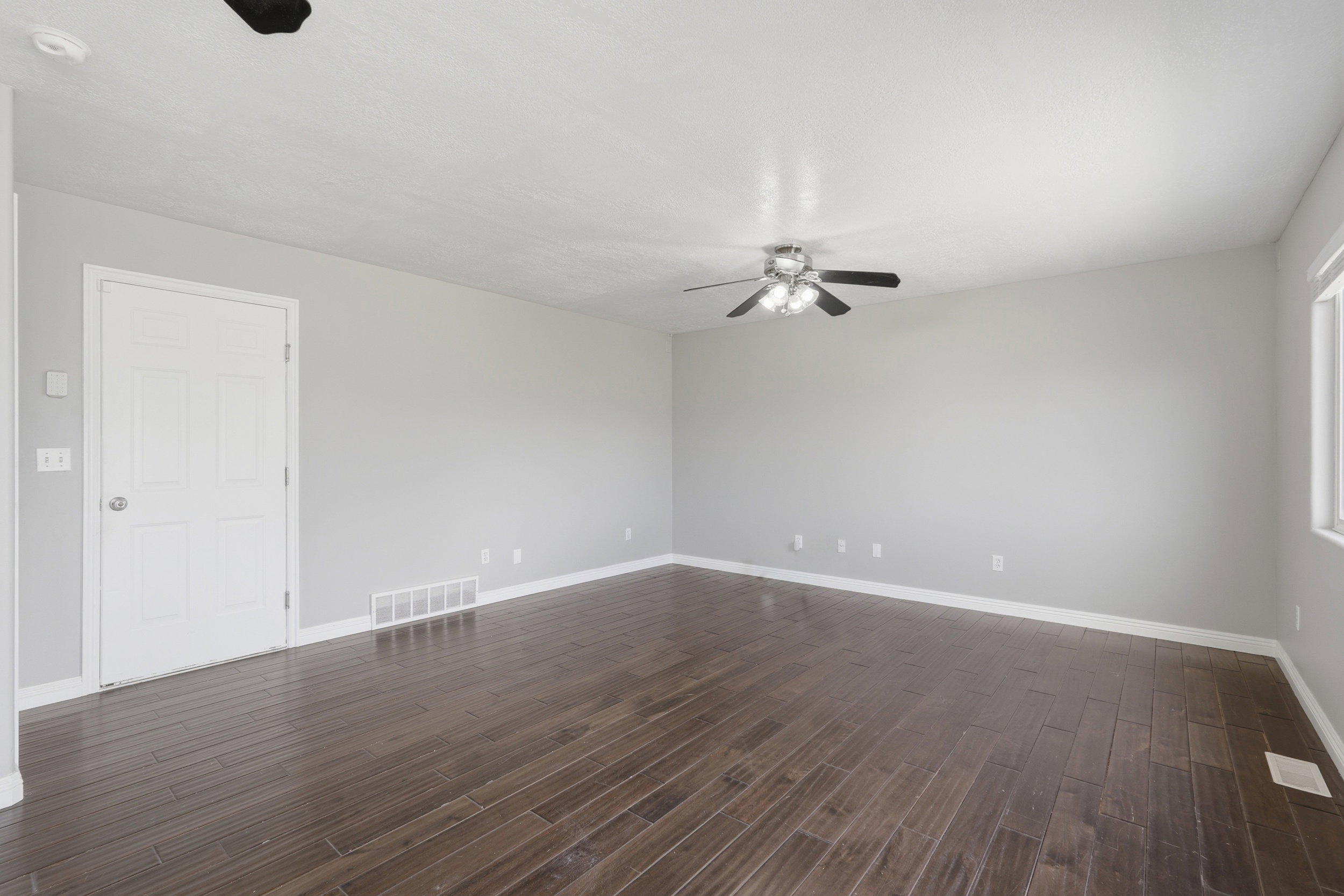 Spacious interior with rich wood-finish flooring, light gray wall tones, and white trim