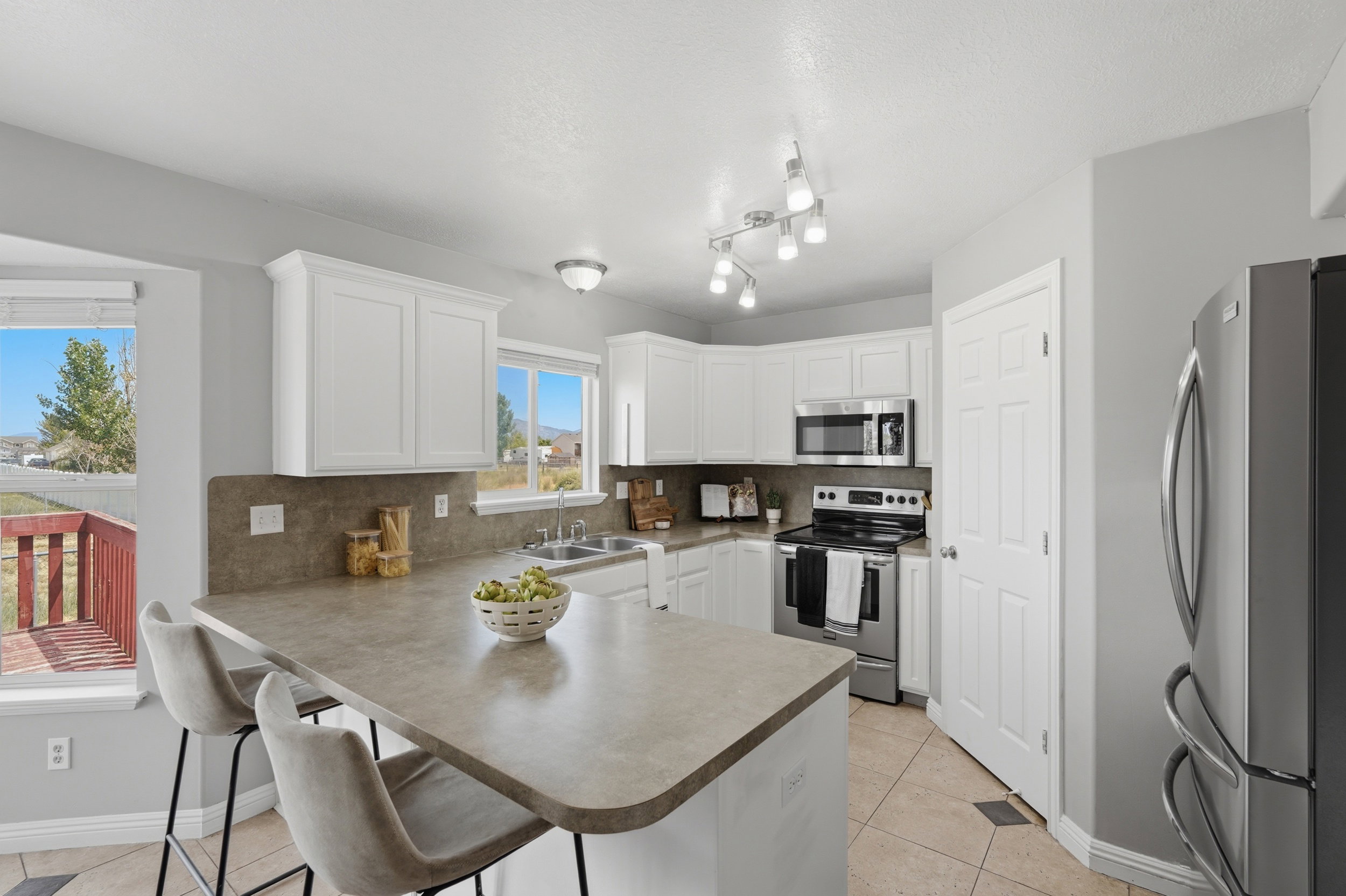 Kitchen featuring white cabinetry, gray countertops, stainless steel appliances, and a breakfast bar