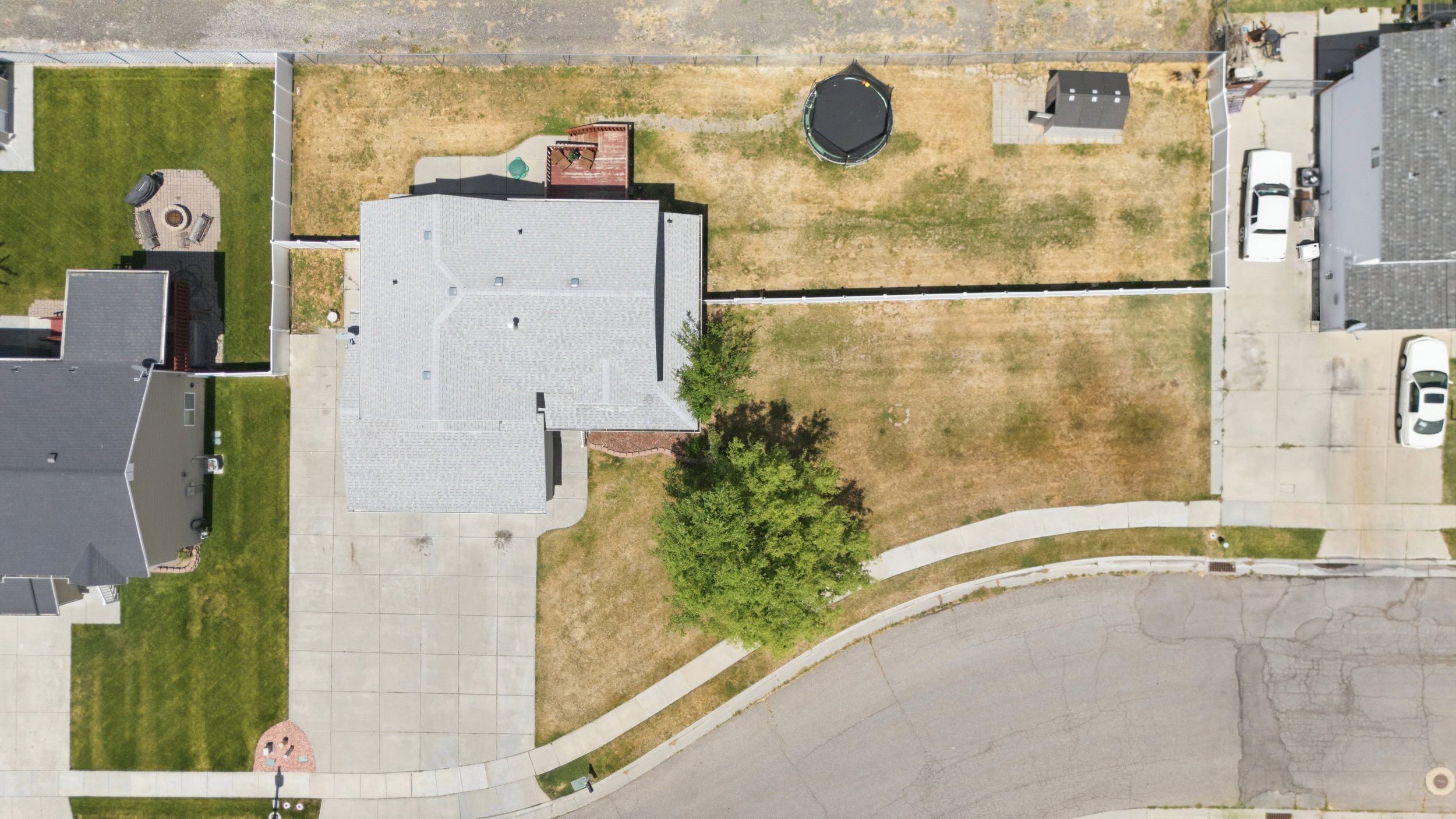Single-family residence featuring an expansive lot with a concrete driveway, a rear deck, and mature landscaping