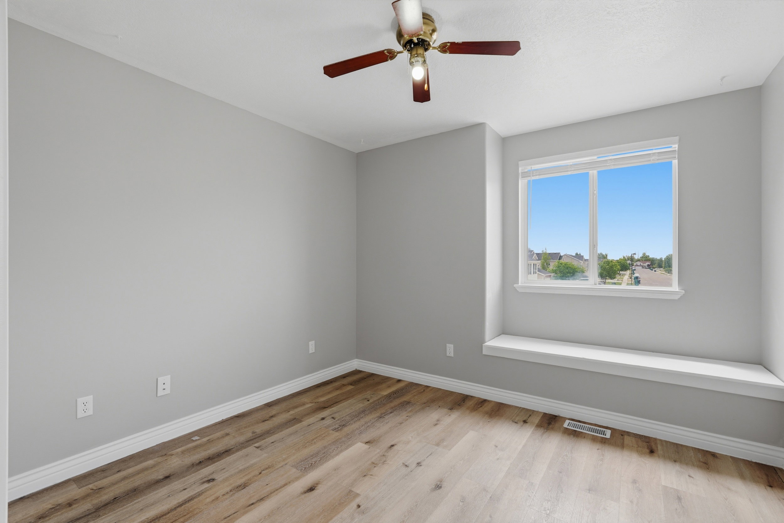 Room featuring light gray walls, wood-finish flooring, and white baseboards
