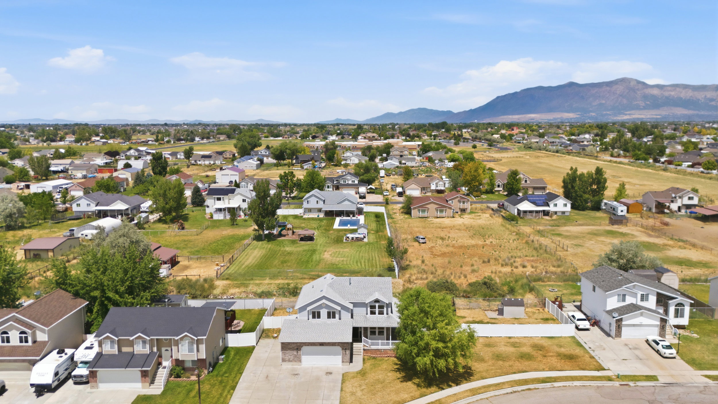 Expansive residential area featuring a variety of single-family homes, clear skies, and distant mountains