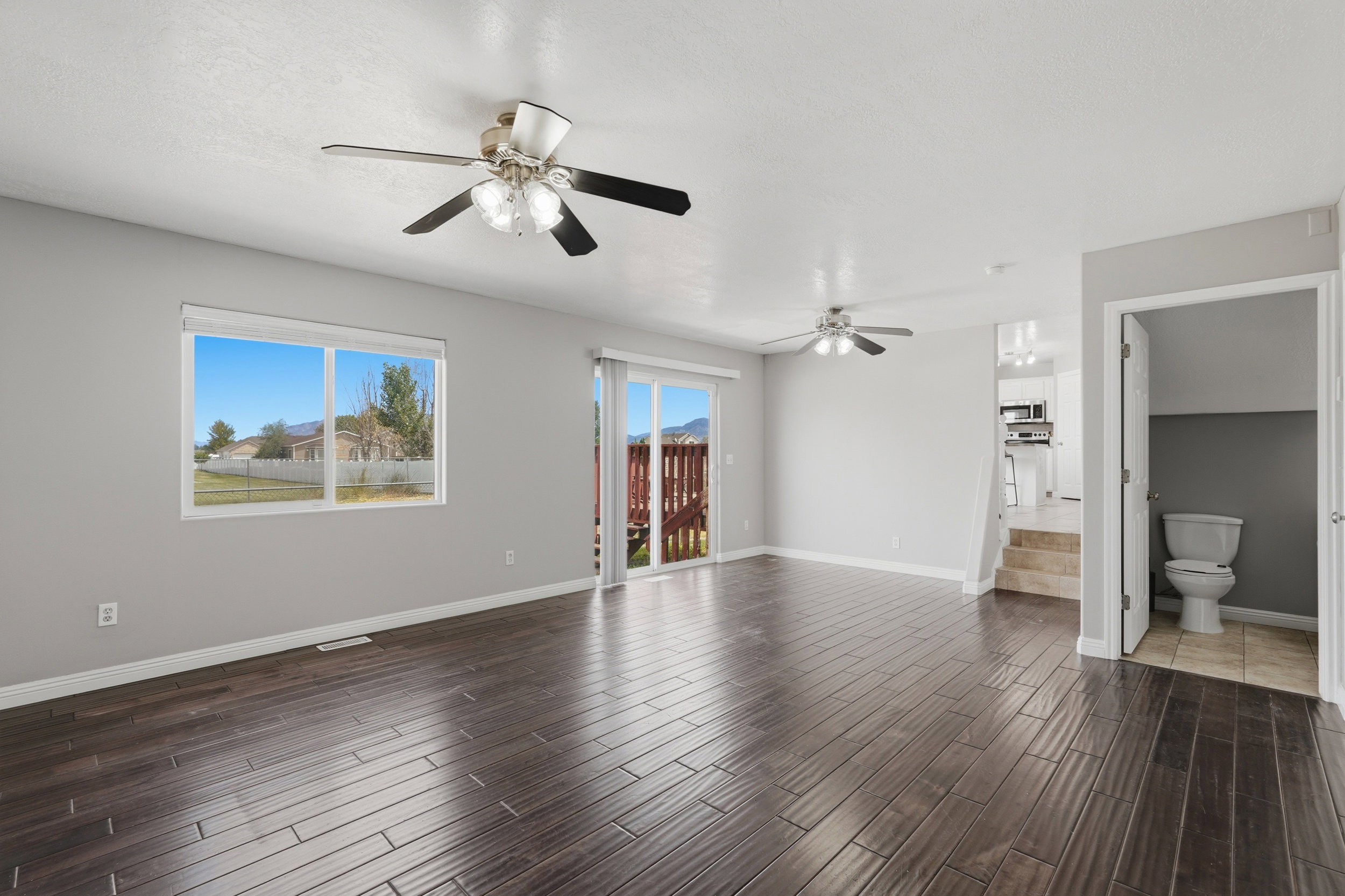 Spacious room featuring dark wood-finish flooring, light gray walls, and white trim