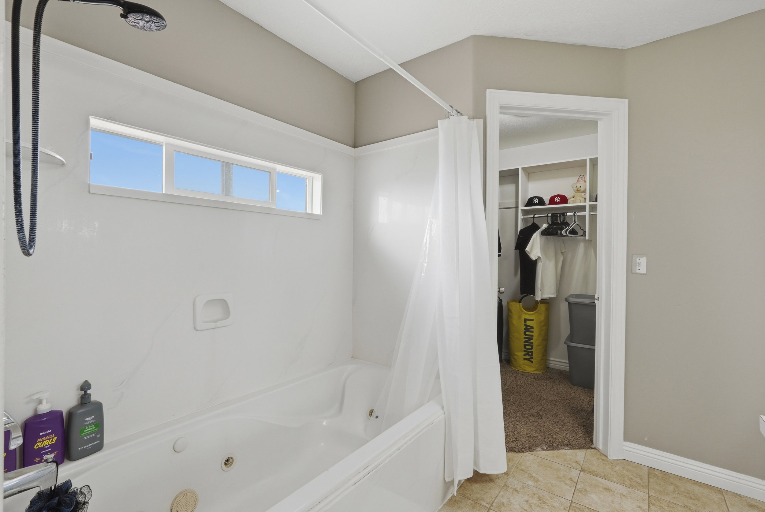 White jetted tub with shower combination and overhead window