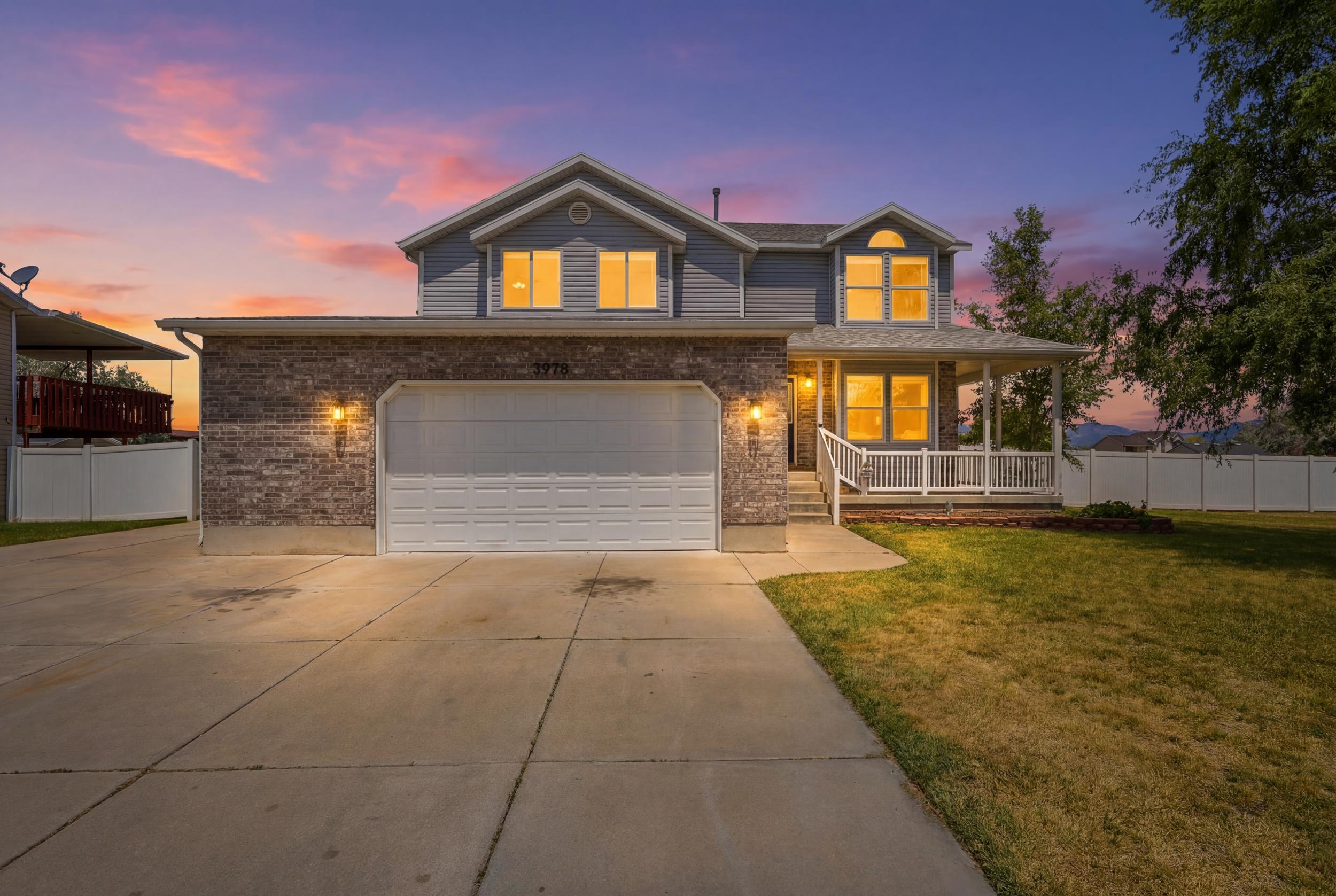 Two-story residence featuring a covered front porch with white railings, a two-car garage, and a concrete driveway