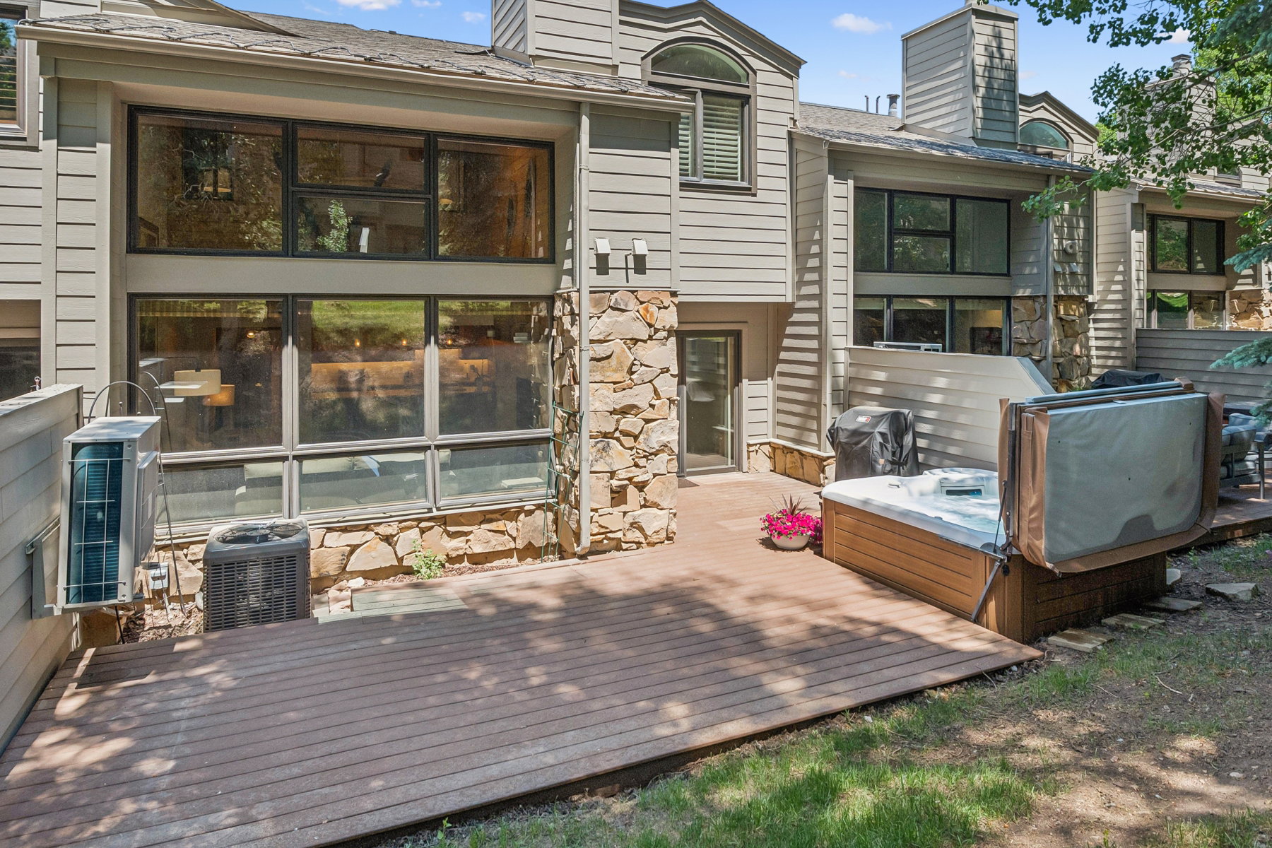 Wood-finish composite deck offering an outdoor spa, built-in grill, and stone veneer accents