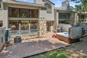 Wood-finish composite deck offering an outdoor spa, built-in grill, and stone veneer accents