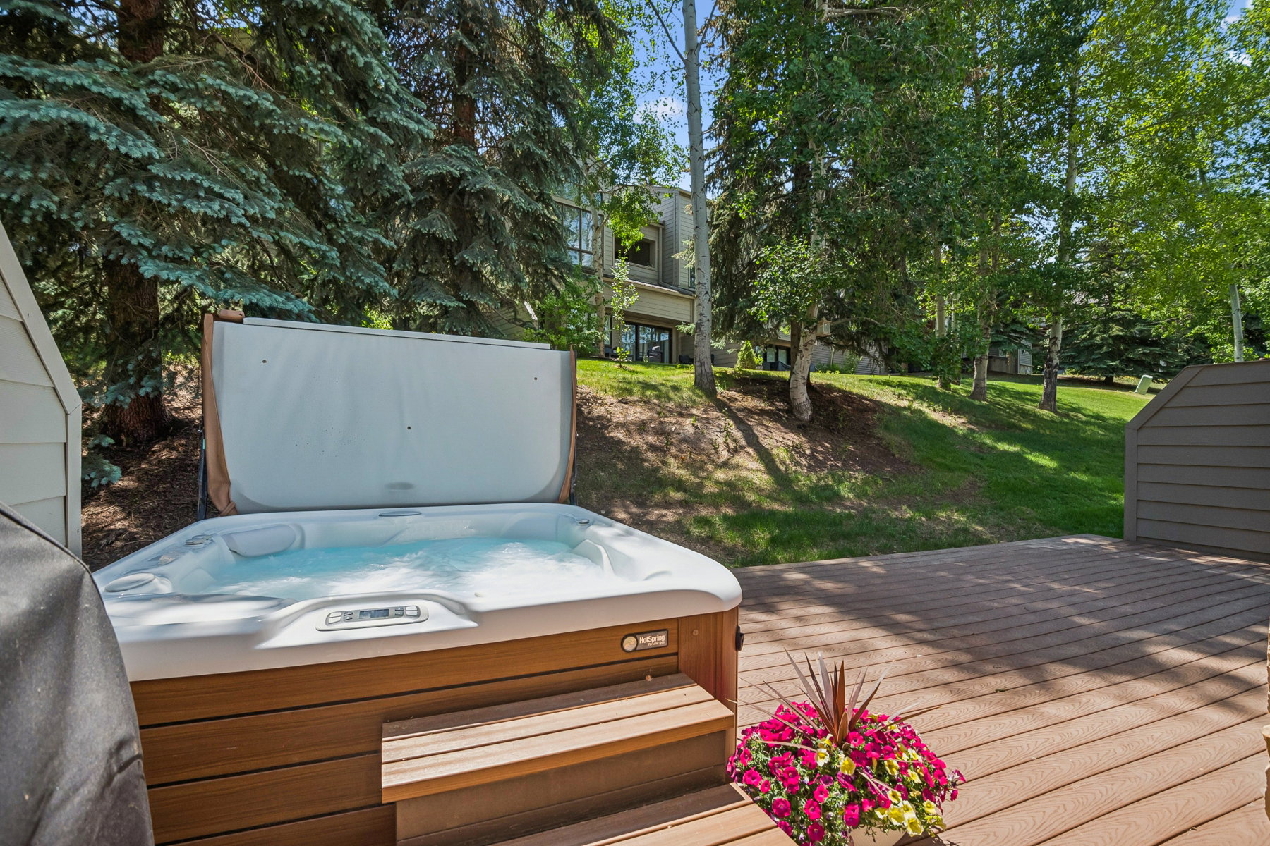 Outdoor hot tub with wood-finish siding, situated on a composite decking platform