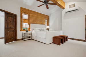 Bedroom with light-toned carpeting, wood-paneled accent wall, exposed wood beam, ceiling fan, and dark wood door