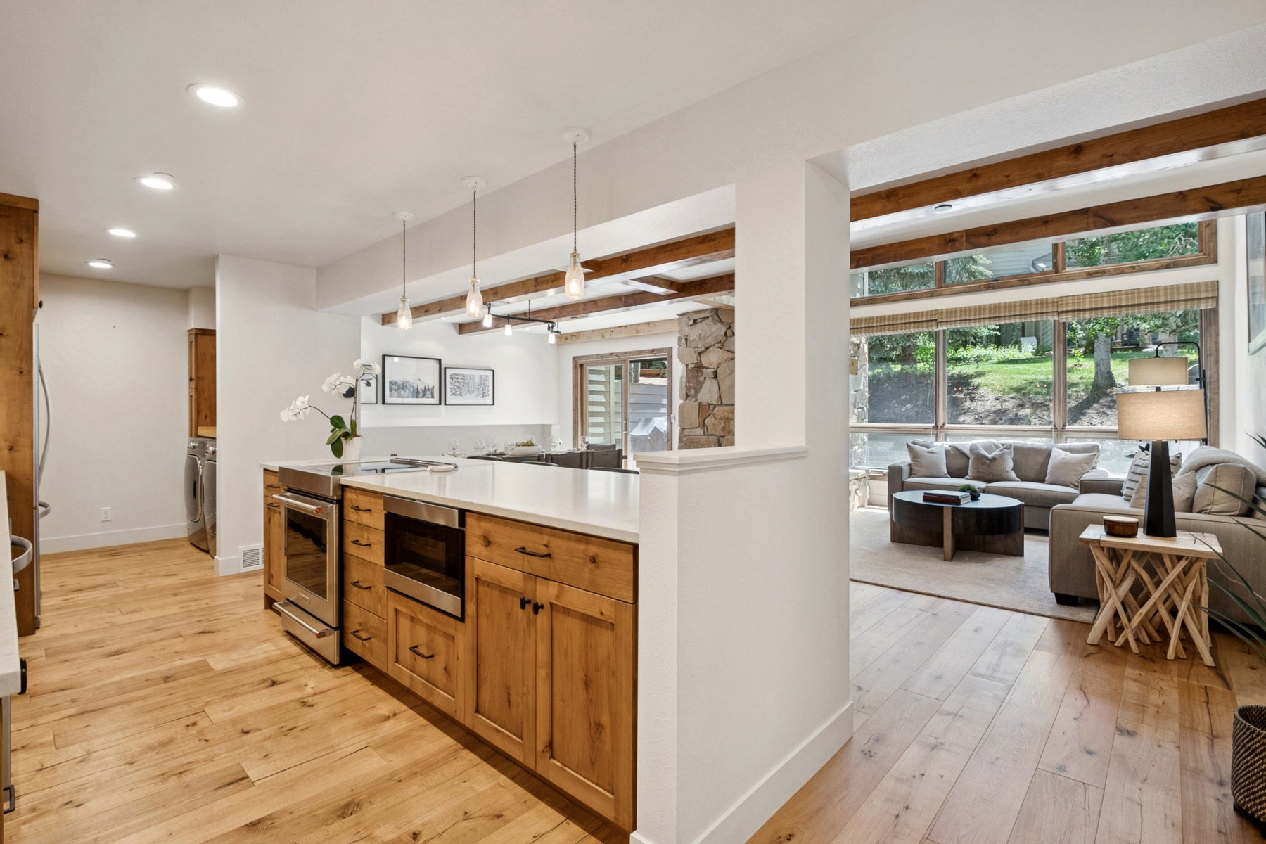 Kitchen island with a light-toned countertop, stainless steel appliances, and natural wood cabinetry