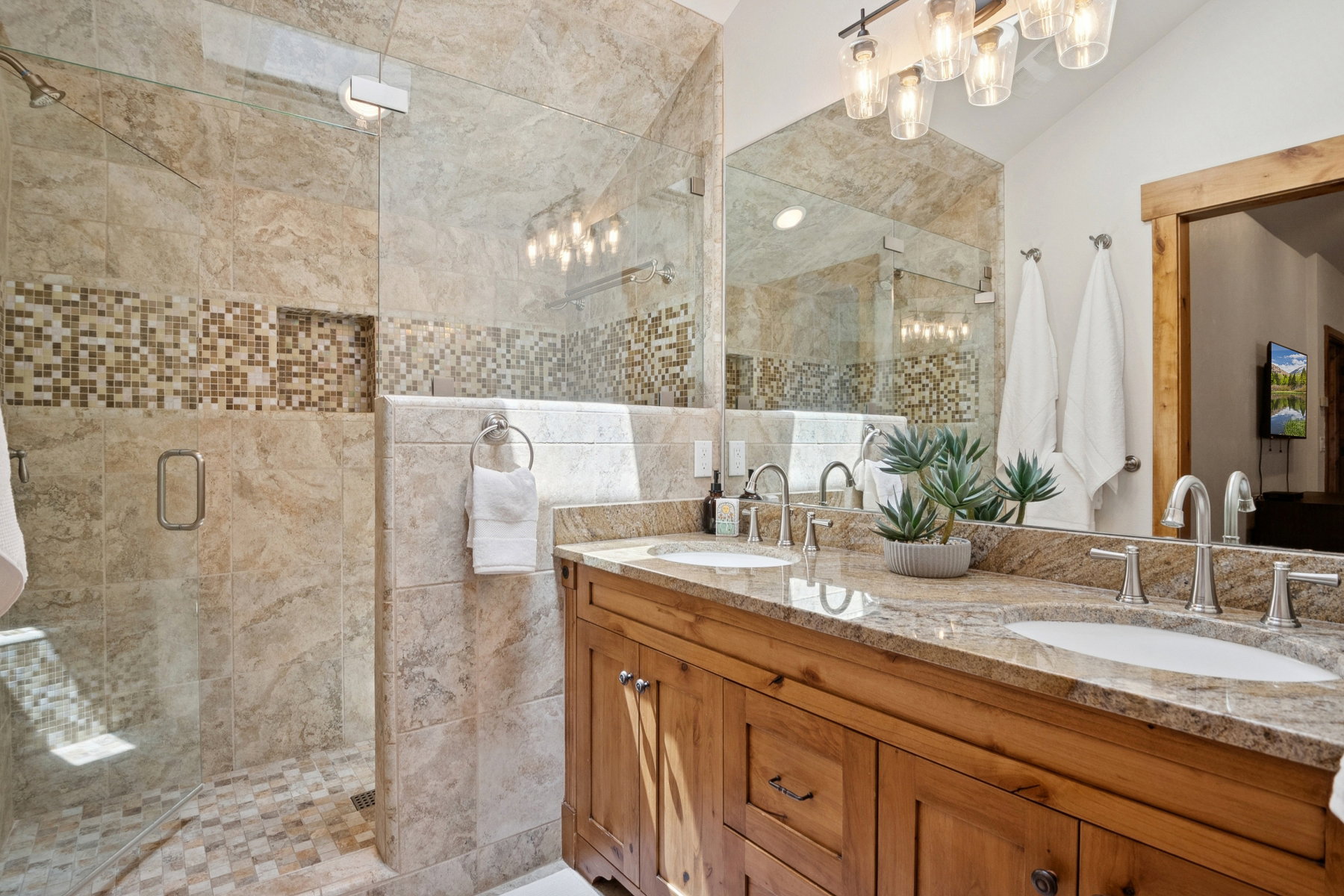 Double vanity with granite countertop and integrated sinks, wood cabinetry, and brushed nickel fixtures