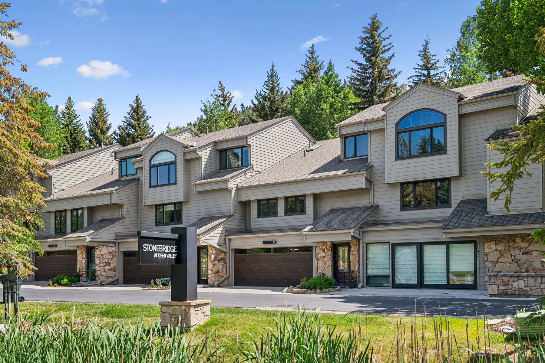 Townhome exteriors featuring neutral siding, stone accents, and dark-framed windows