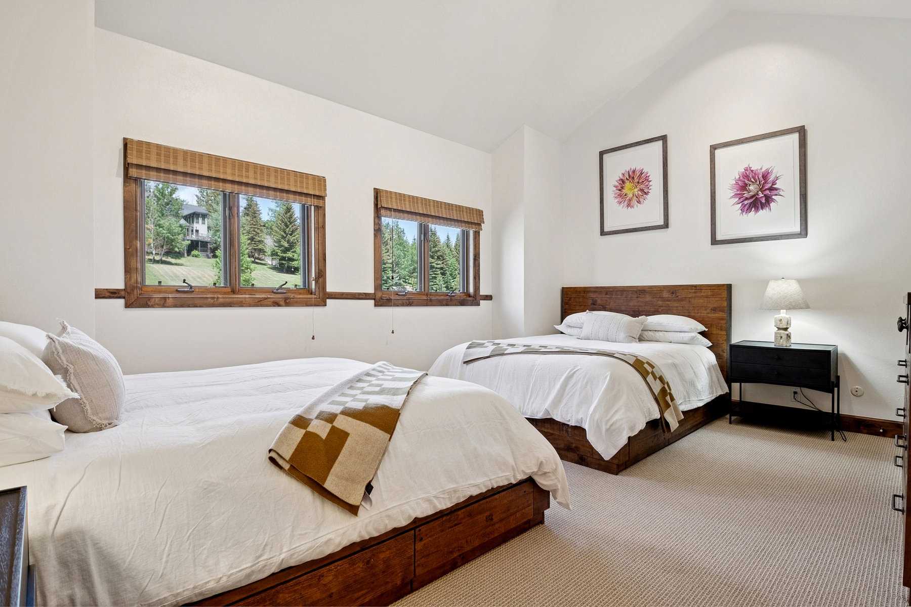 Bedroom featuring a vaulted ceiling and two windows with wood frames and woven shades