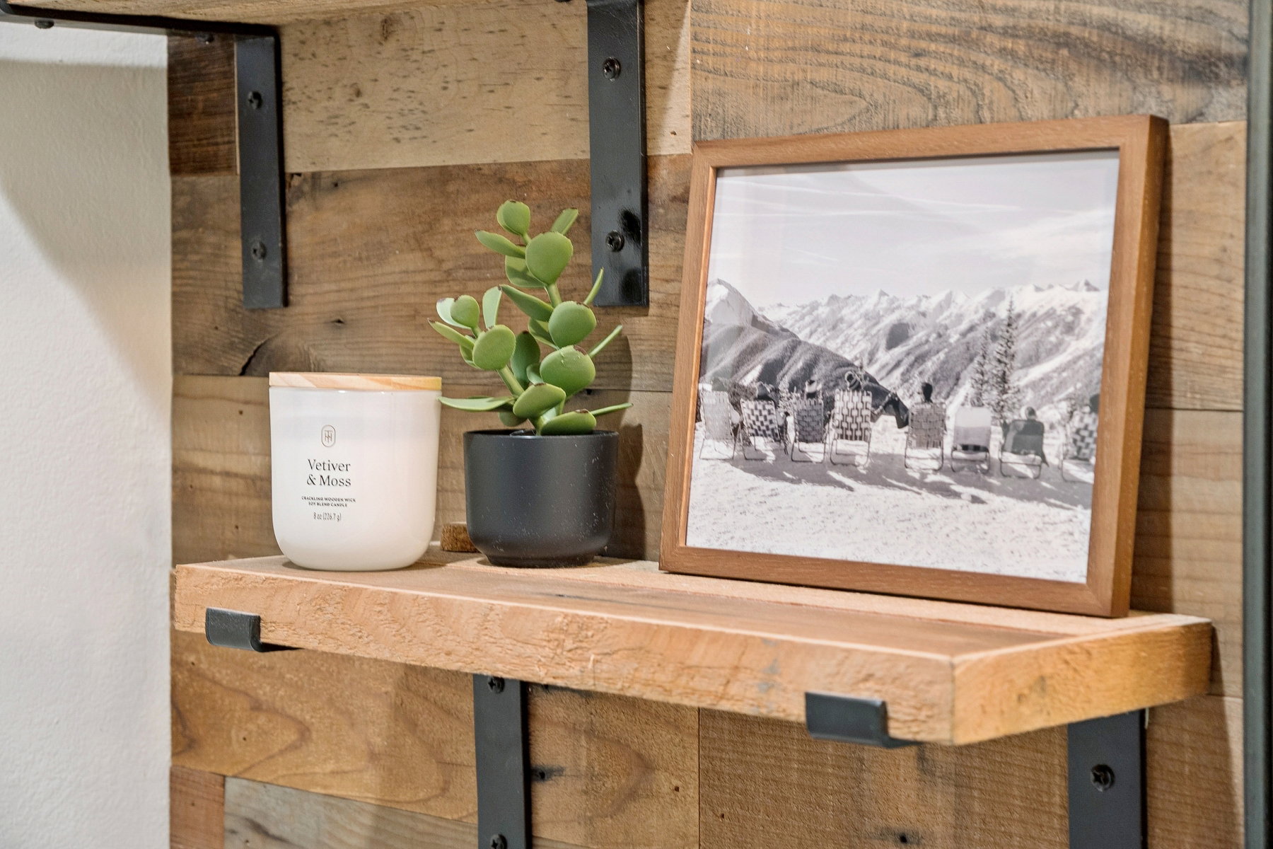Reclaimed wood accent wall featuring a floating wooden shelf with robust black metal brackets