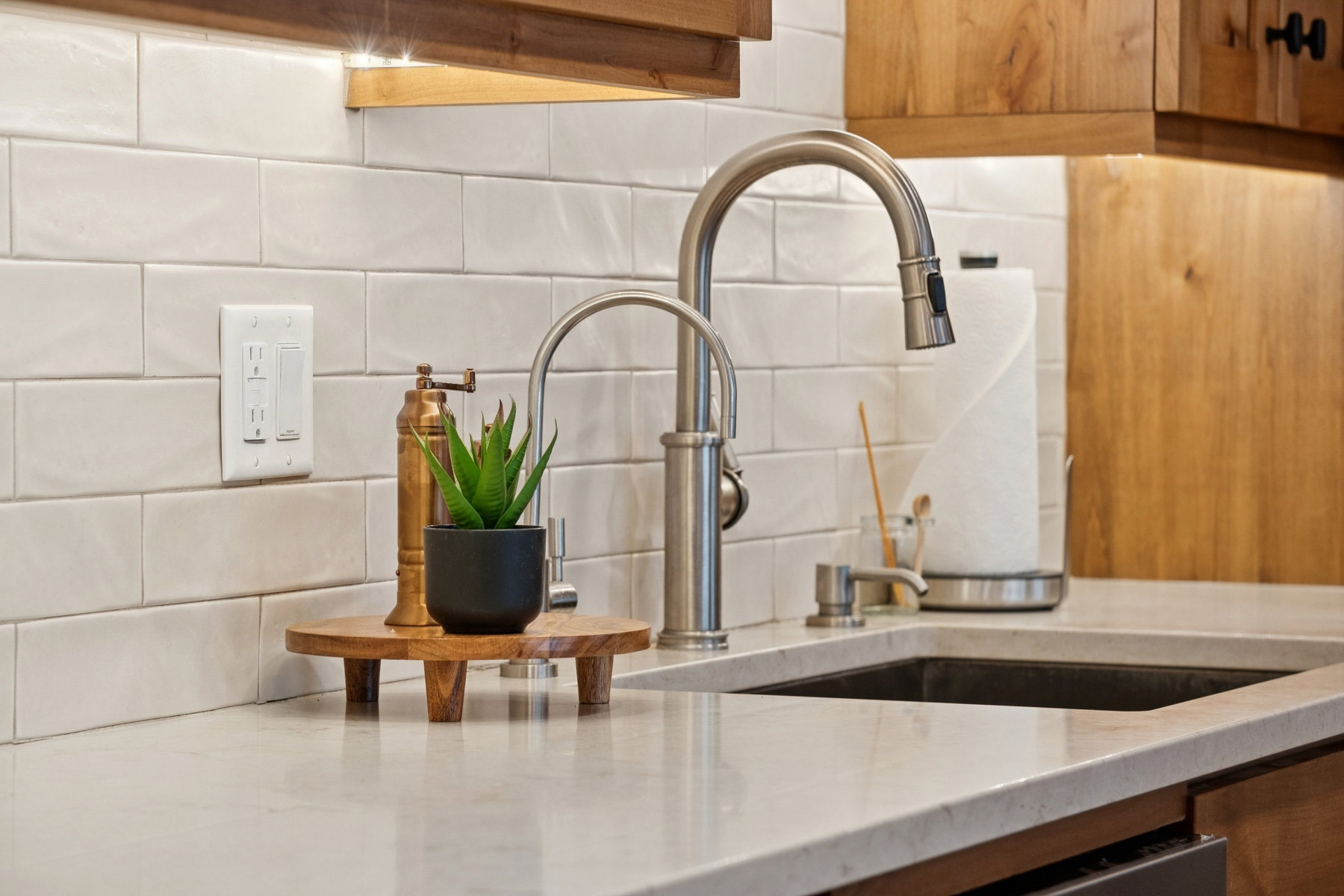 Kitchen featuring light-toned countertops, a black undermount sink, and a brushed nickel gooseneck faucet