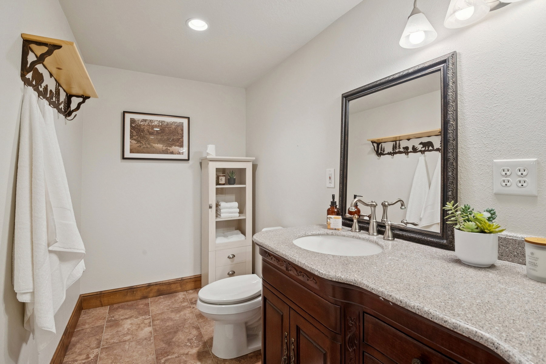 Bathroom featuring a dark wood vanity with a light speckled countertop, undermount sink, and polished chrome faucet