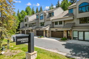 Exterior townhome complex featuring stone accents and wood-finish garage doors