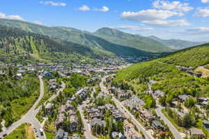 Expansive mountain landscape featuring a valley with residential properties, winding roads, and a town center
