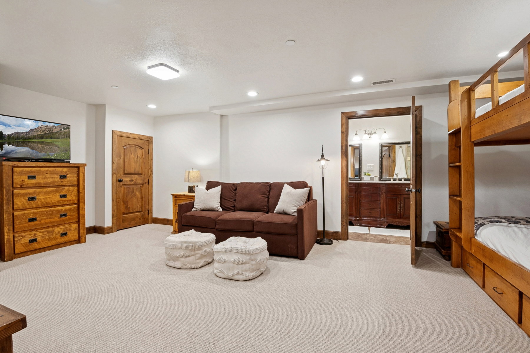 Carpeted interior space featuring recessed lighting, a wooden door frame, and a partial view of a bathroom vanity with dual sinks
