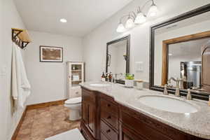 Dual vanity featuring a wood-finish cabinet with decorative carving, light-toned countertop, and dual sinks with brushed nickel faucets