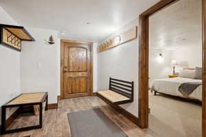 Entryway featuring wood-finish flooring, a solid wood door with an arch-top panel, and a built-in wall bench with wood and metal accents