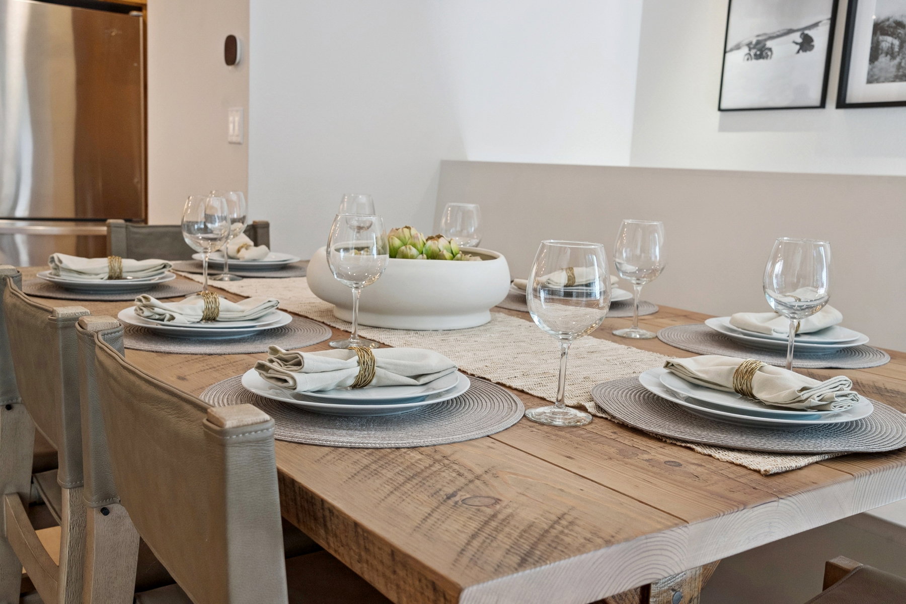Dining area featuring a rustic wood-finish table, built-in bench seating, a stainless steel refrigerator, and modern wall decor