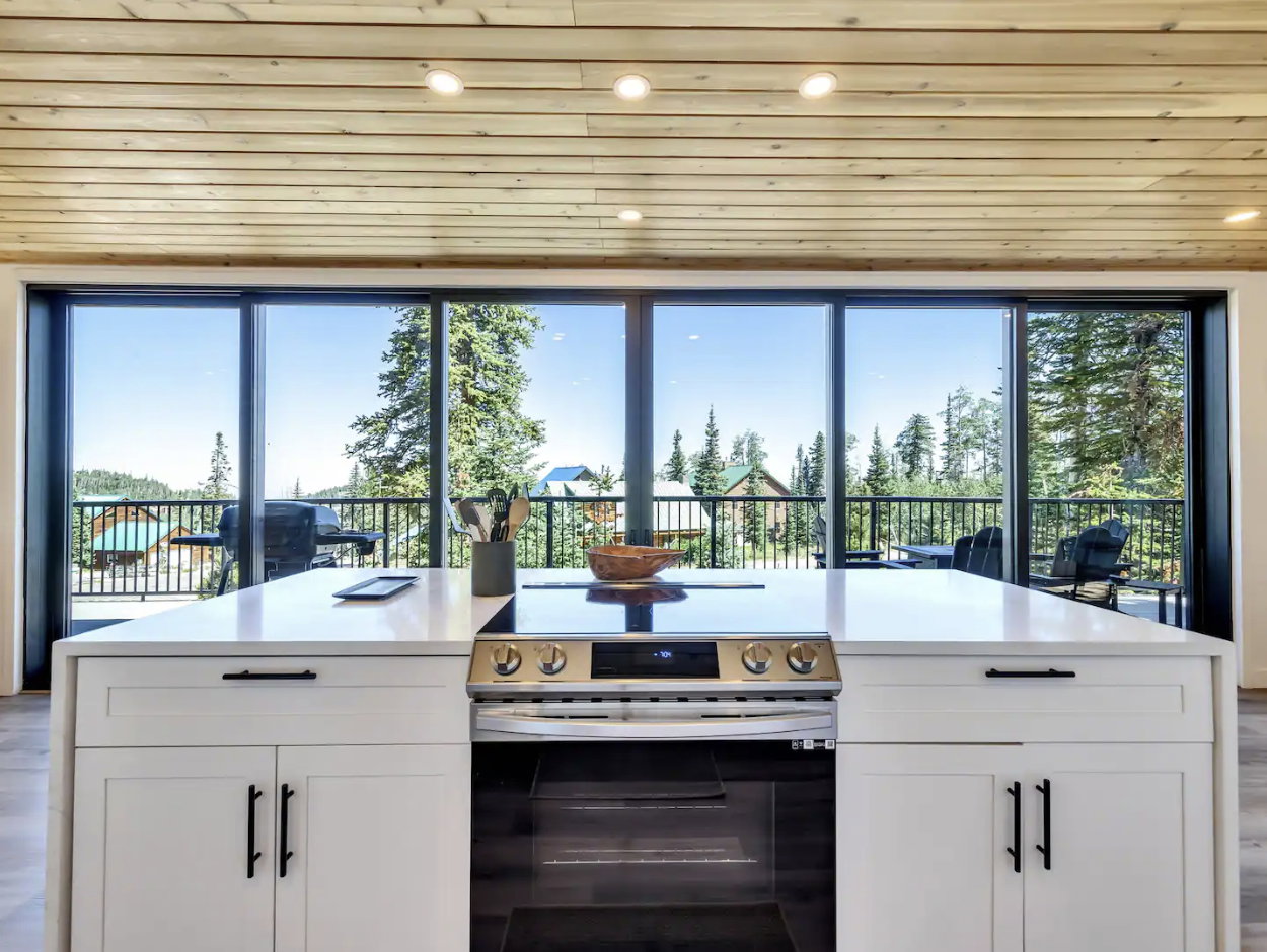 Central kitchen island with a built-in electric range, white shaker-style cabinetry, and a light-toned countertop