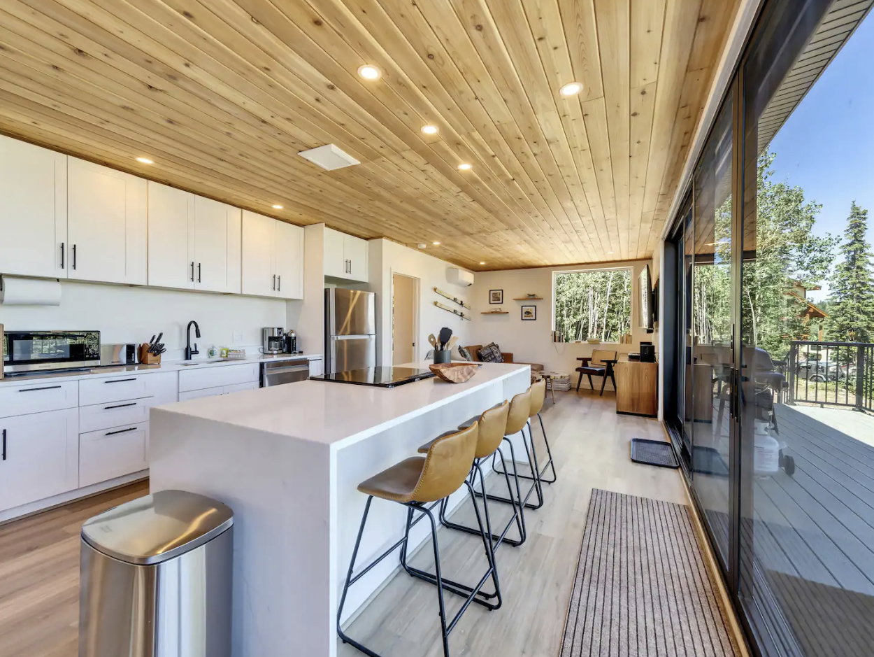 Open-concept living space with a slatted wood ceiling and recessed lighting